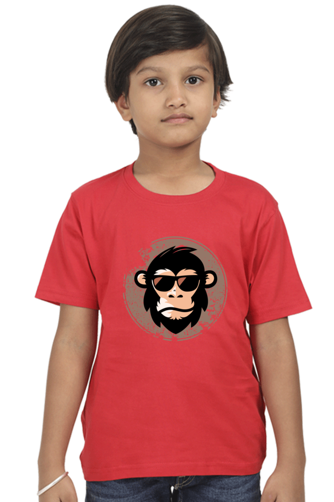 A young child with short brown hair stands against a white background, wearing the TuckTribe COOL CHIMP BOYS T-SHIRT featuring a chimpanzee with sunglasses.