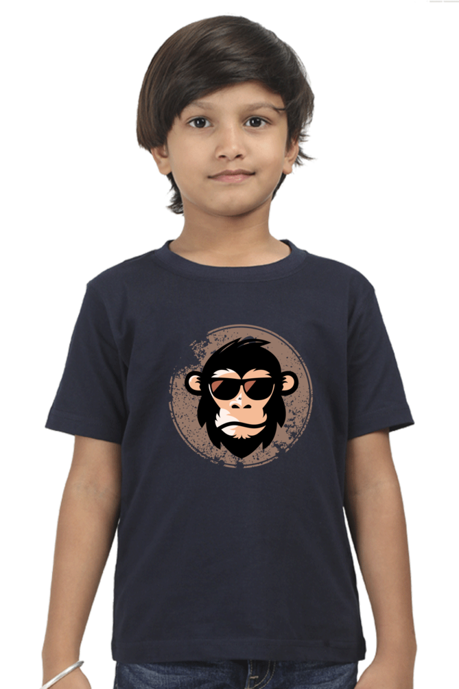 A child models the COOL CHIMP BOYS T-SHIRT by TuckTribe, featuring a trendy chimp with sunglasses on a navy blue tee. The plain white background enhances the designs appeal.