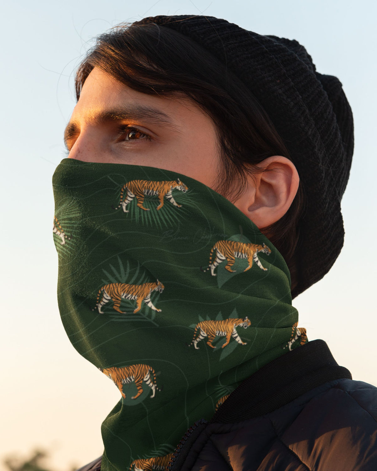 side profile of a man wearing a Tiger Walk Neck Gaiter featuring walking Bengal tiger prints on a dark forest-green background by Tucktribe.