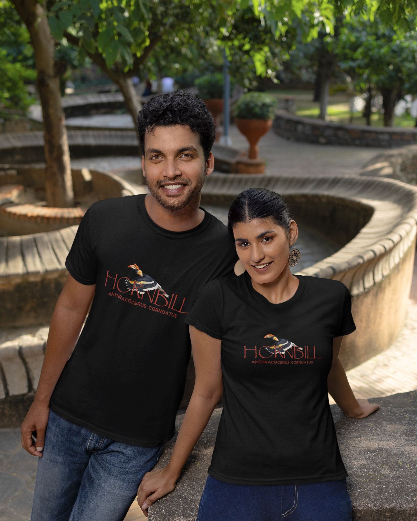 Two people wearing tucktribe black t-shirts with a hornbill design in an outdoor setting.
