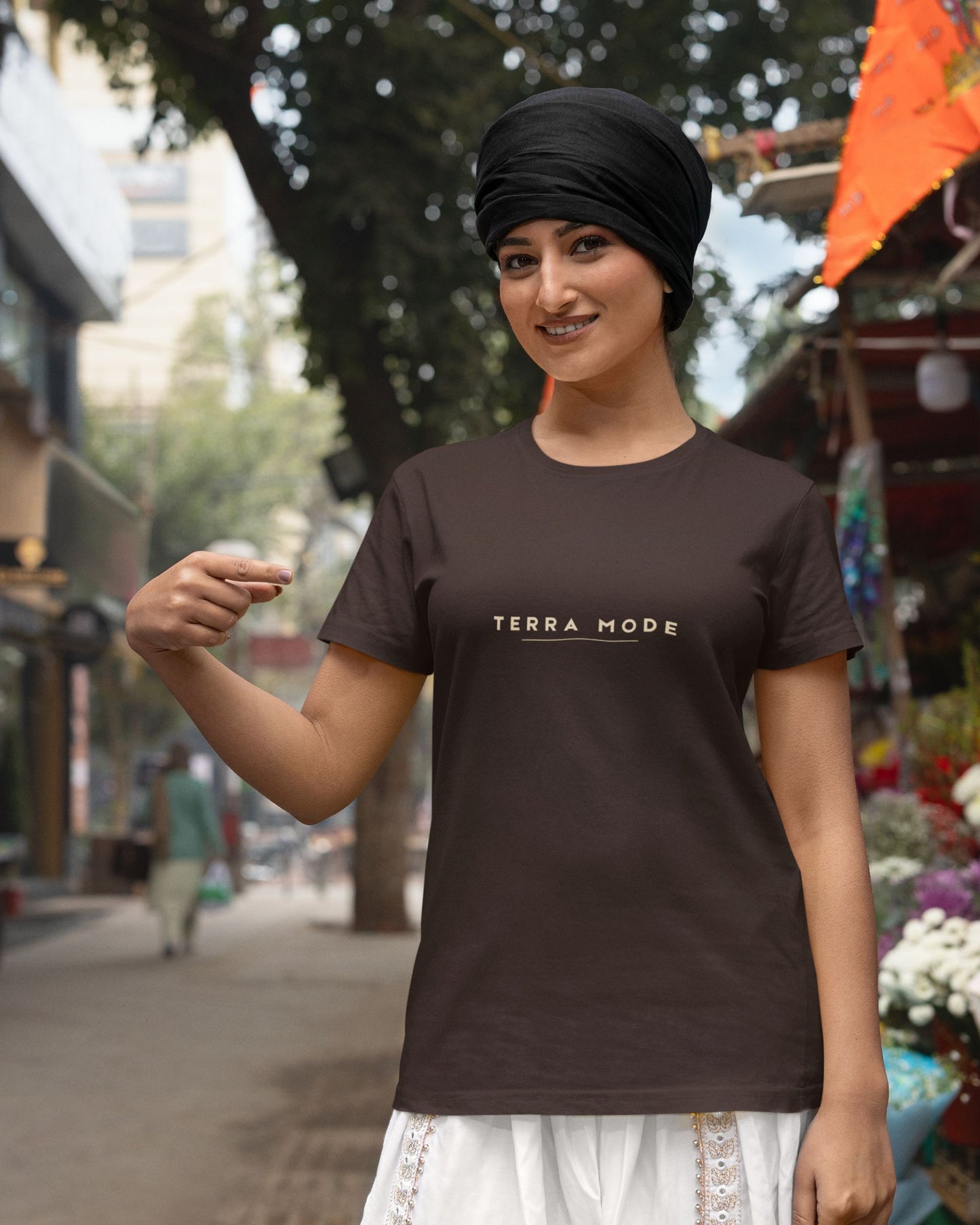 Woman wearing a Tucktribe brown 'Terra Mode' t-shirt in an outdoor setting.