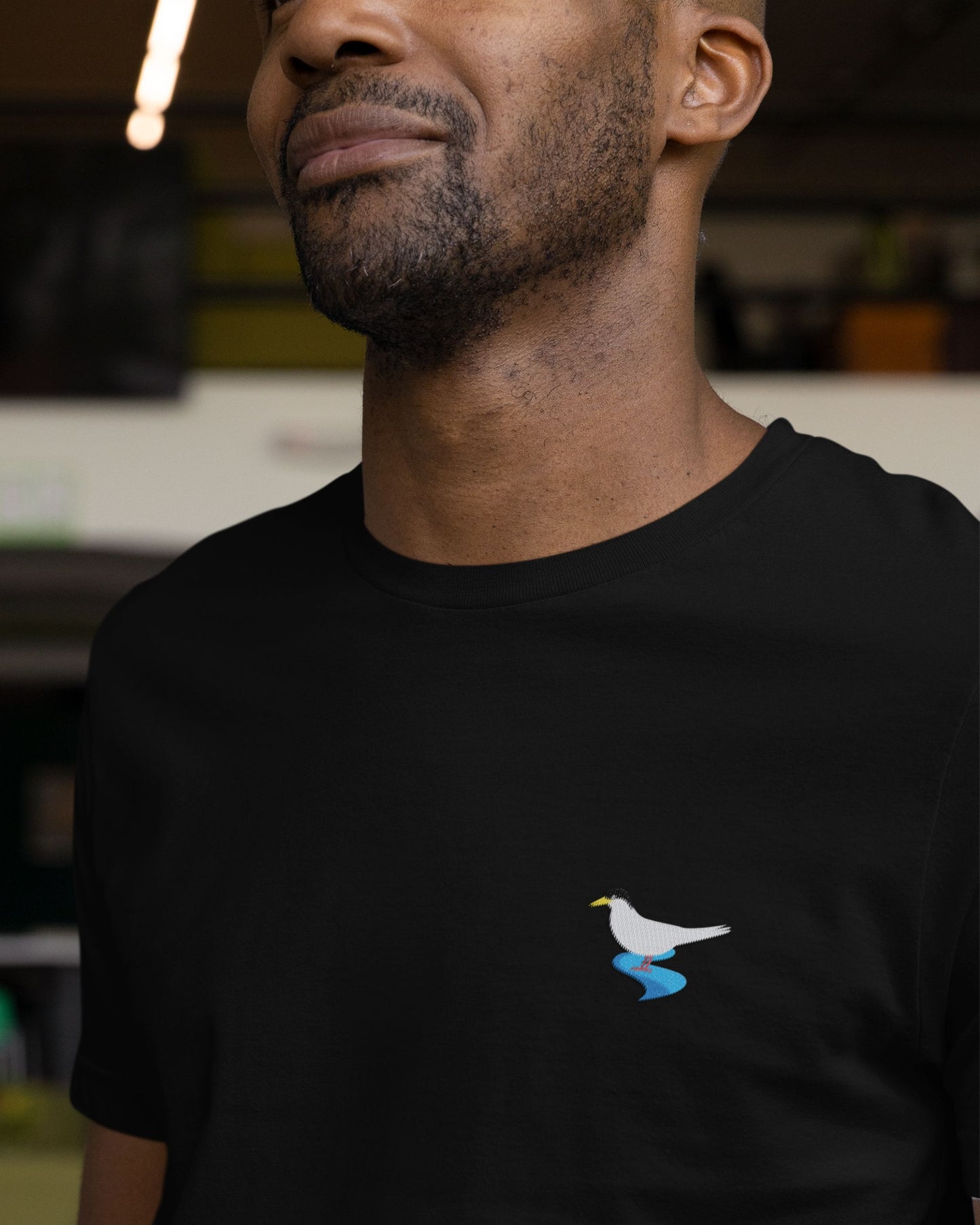 Man wearing black Supima cotton t-shirt with embroidered River Tern bird design by Tucktribe