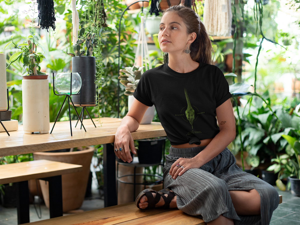 woman wearing a Black graphic T-shirt featuring detailed green vine snake artwork with Silent Unseen typography