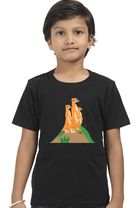 A child wears the MEERKAT Boys T-SHIRT by TuckTribe, showcasing adorable illustrations of three meerkats perched on a grassy mound against a plain white background.
