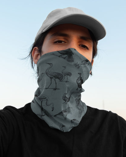 Person wearing a patterned face cover and cap against a clear sky.