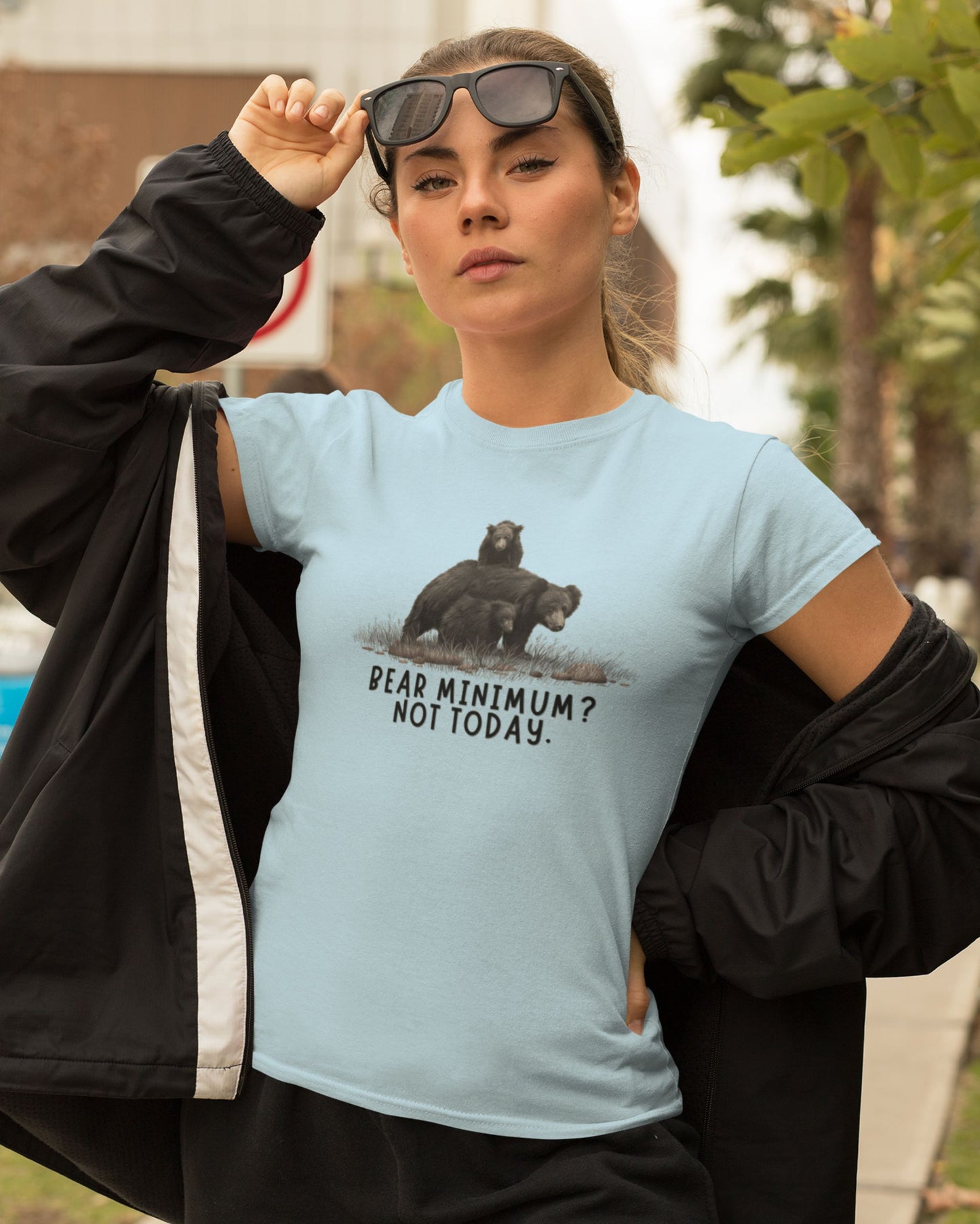 Woman wearing a light blue t-shirt with a bear graphic and text, outdoors.