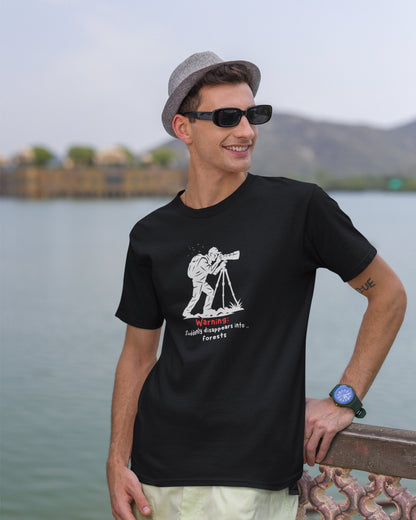 Man wearing a black t-shirt with a graphic design, standing by a body of water.