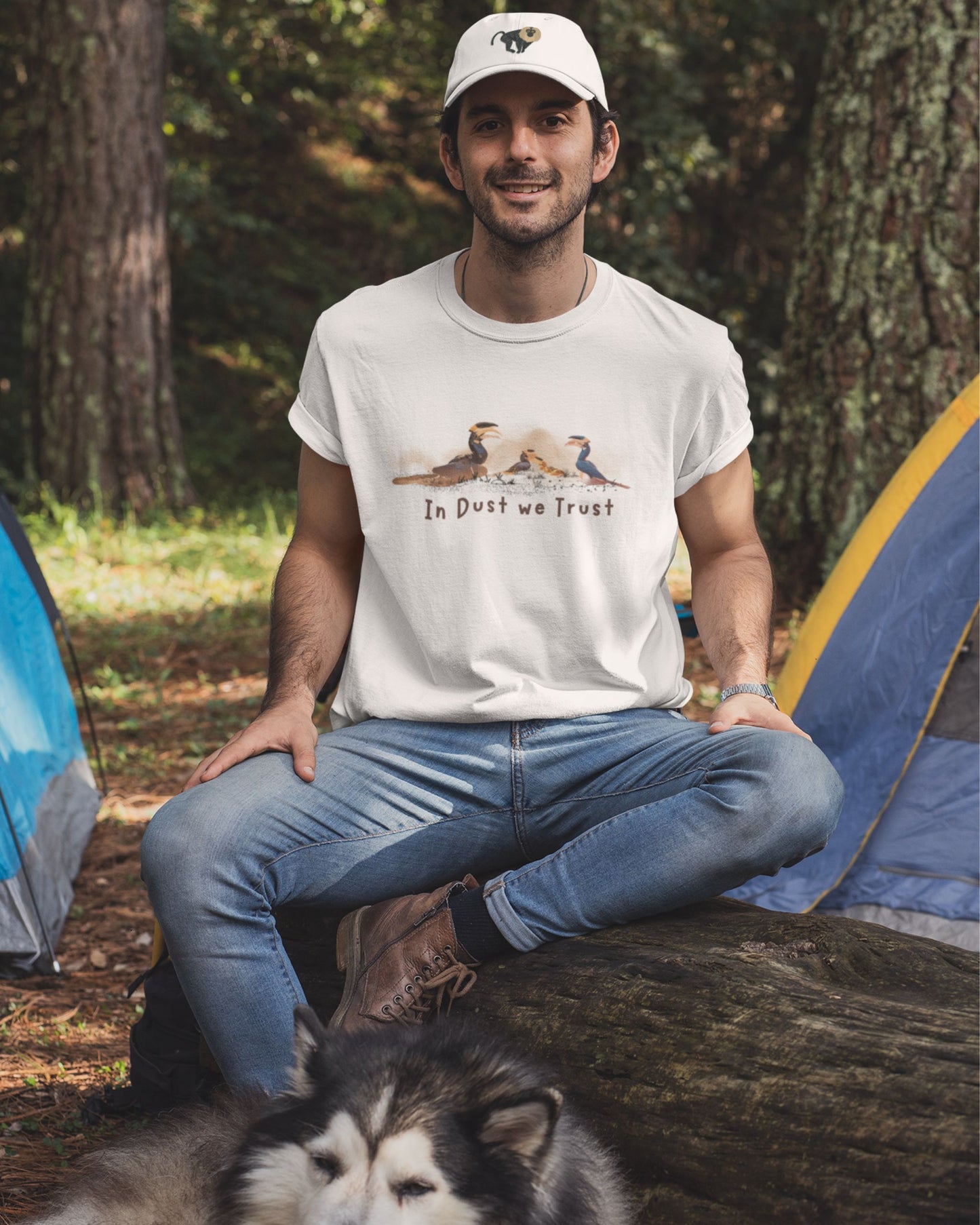 Man sitting outdoors with a dog, wearing a t-shirt with a graphic design.