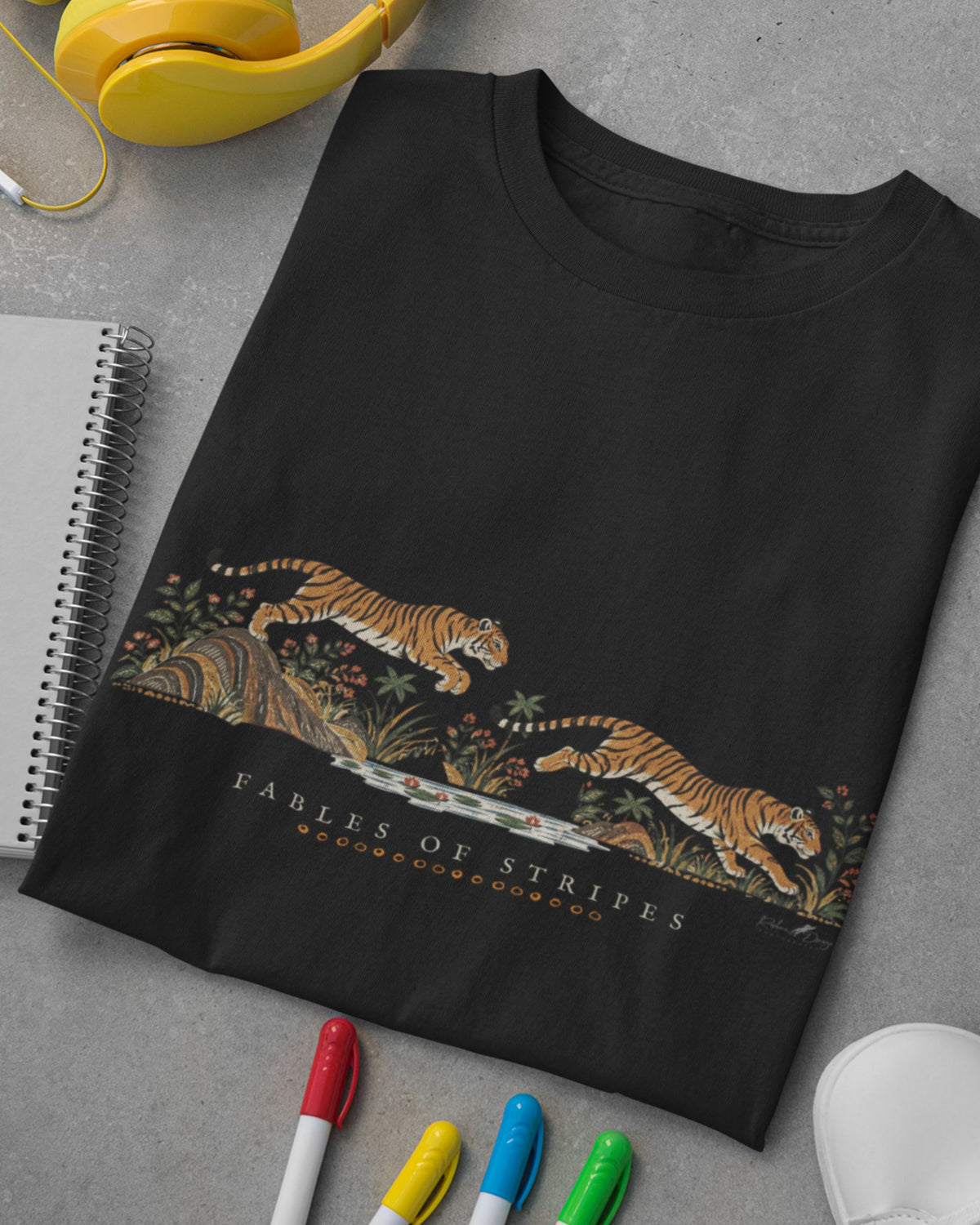 black Tucktribe Fables of Stripes unisex tiger graphic T-shirt placed along with some books and pens