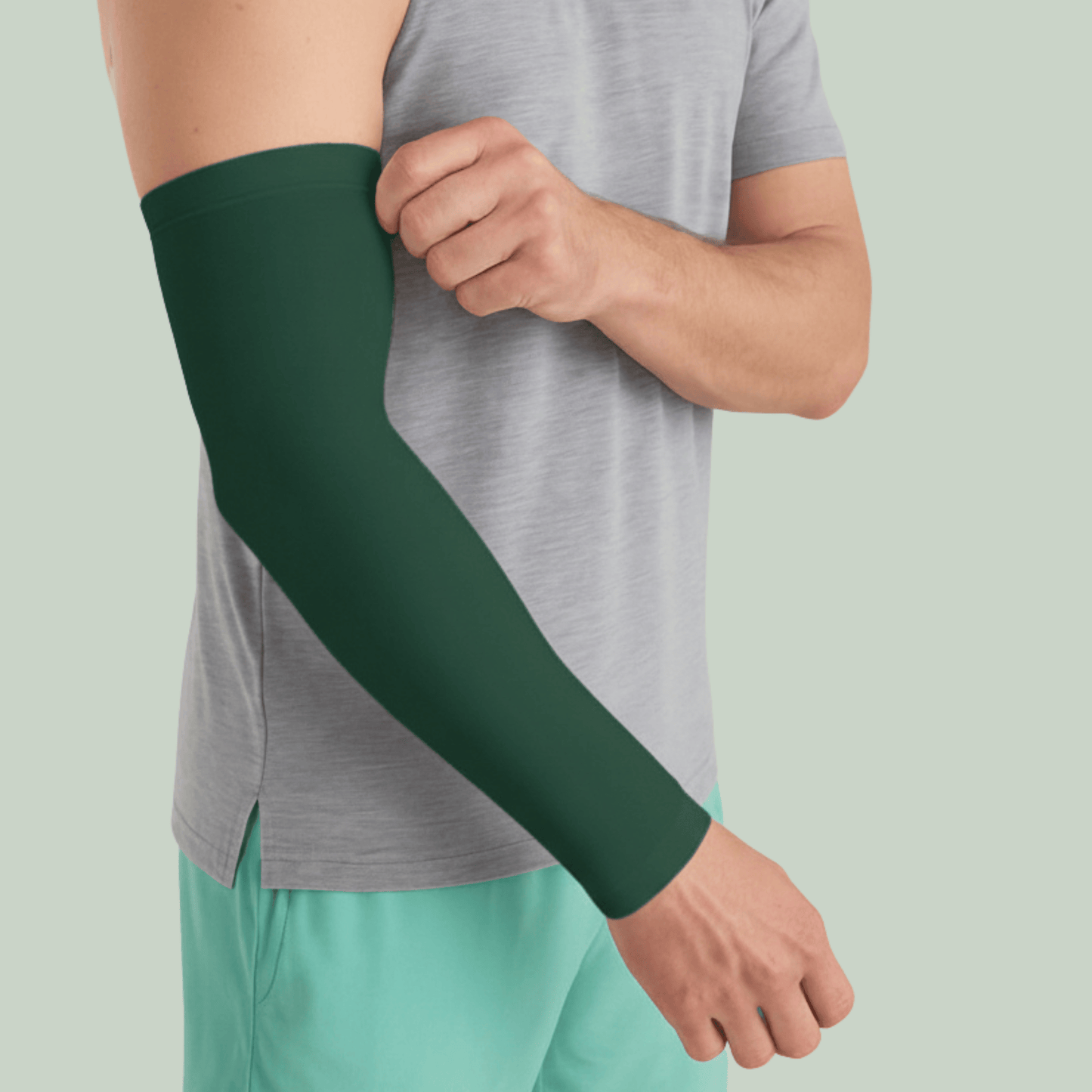 Person wearing a tucktribe forest green arm sleeve on a light green background