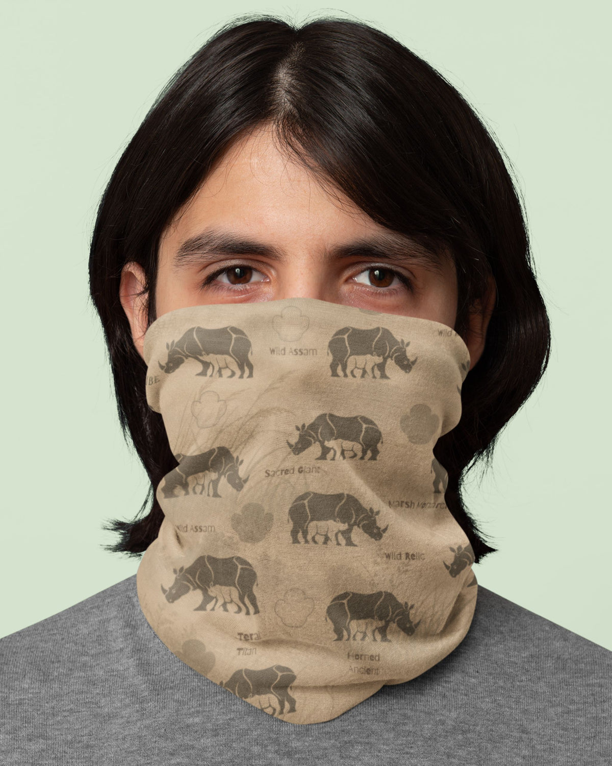 A person wearing a beige neck gaiter with a brown rhinoceros print, shown from the chest up against a pale green background.