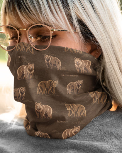 A close-up of a person wearing a brown face mask with a repeating print of Himalayan bears and small text, along with round eyeglasses and a gray top.