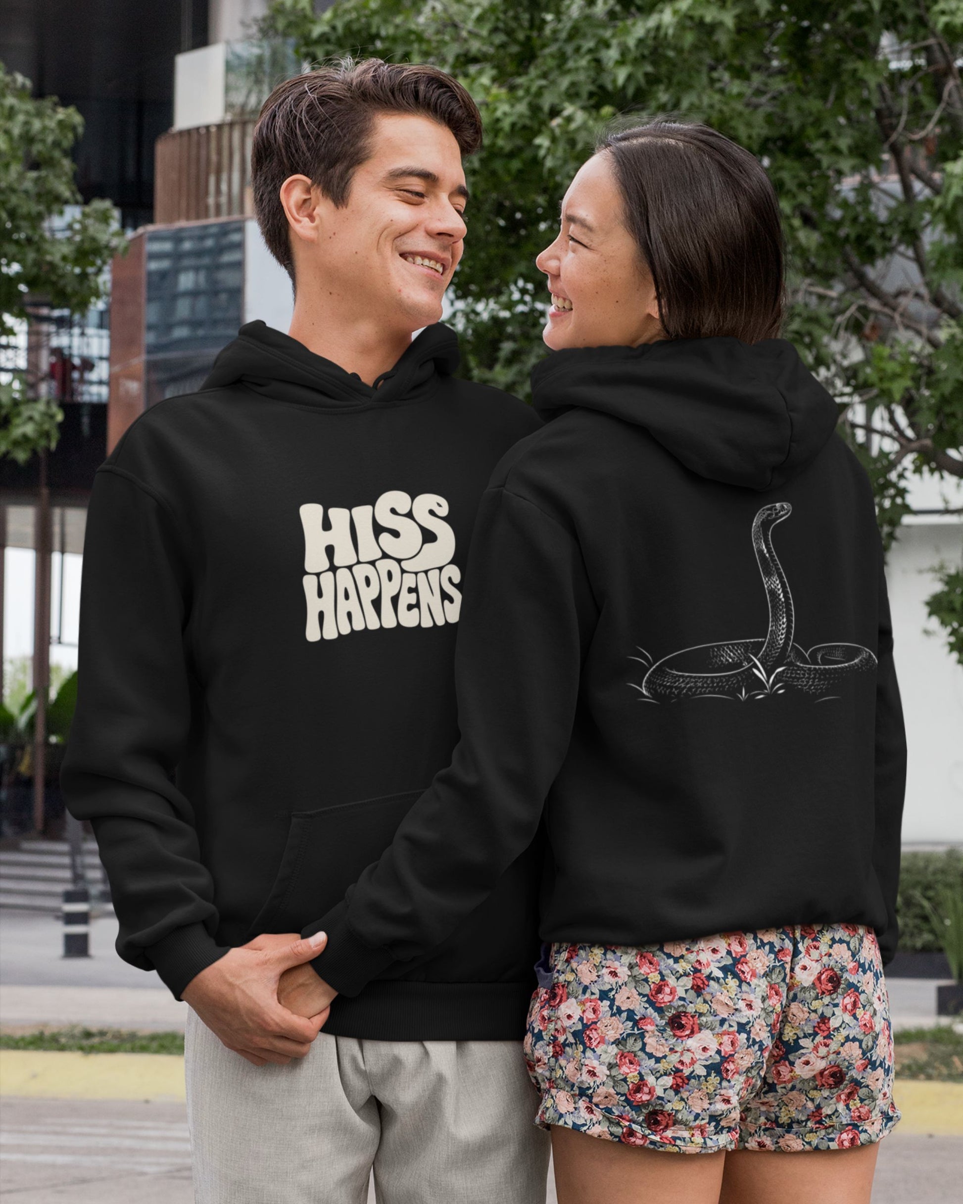 Black unisex hoodie featuring Hiss Happens typography on the front with detailed cobra snake artwork on the back for wildlife lovers.