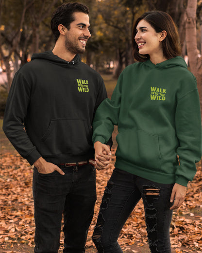 Two people wearing black and green hoodies with 'Walk into the Wild' text, standing in a park.