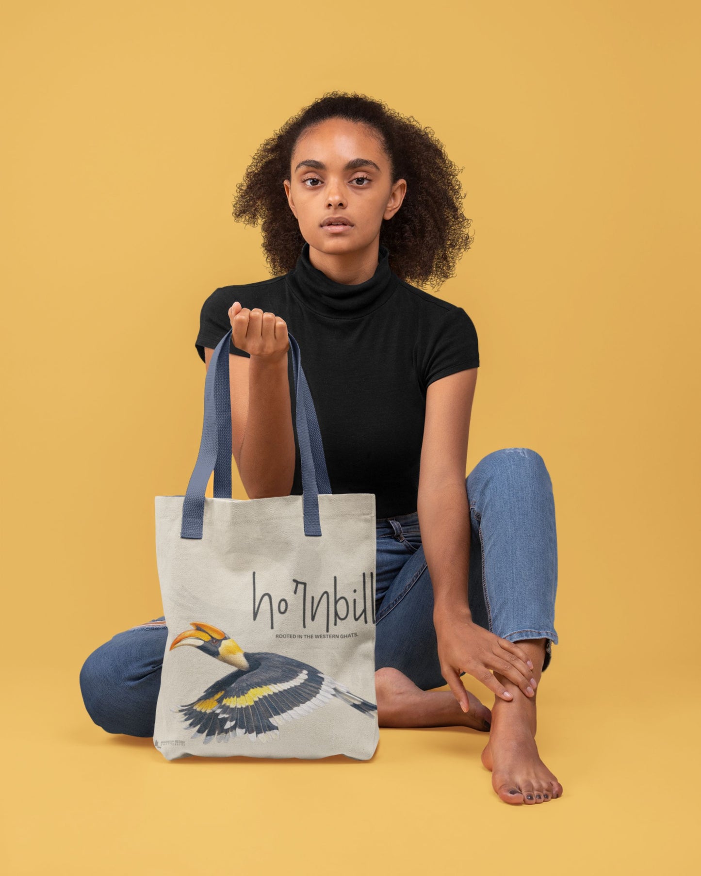 Person holding a Tucktribe tote bag with a hornbill design on a yellow background