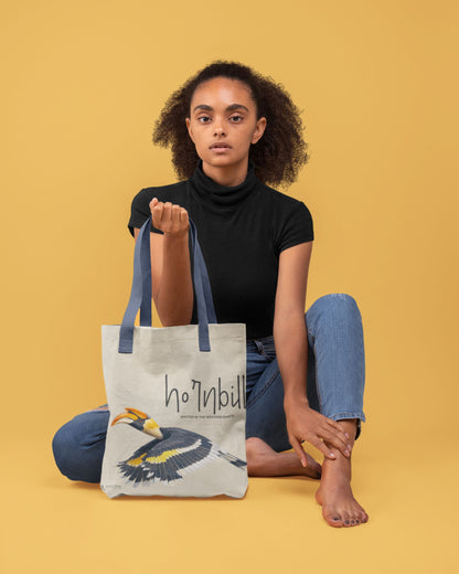 Person holding a Tucktribe tote bag with a hornbill design on a yellow background