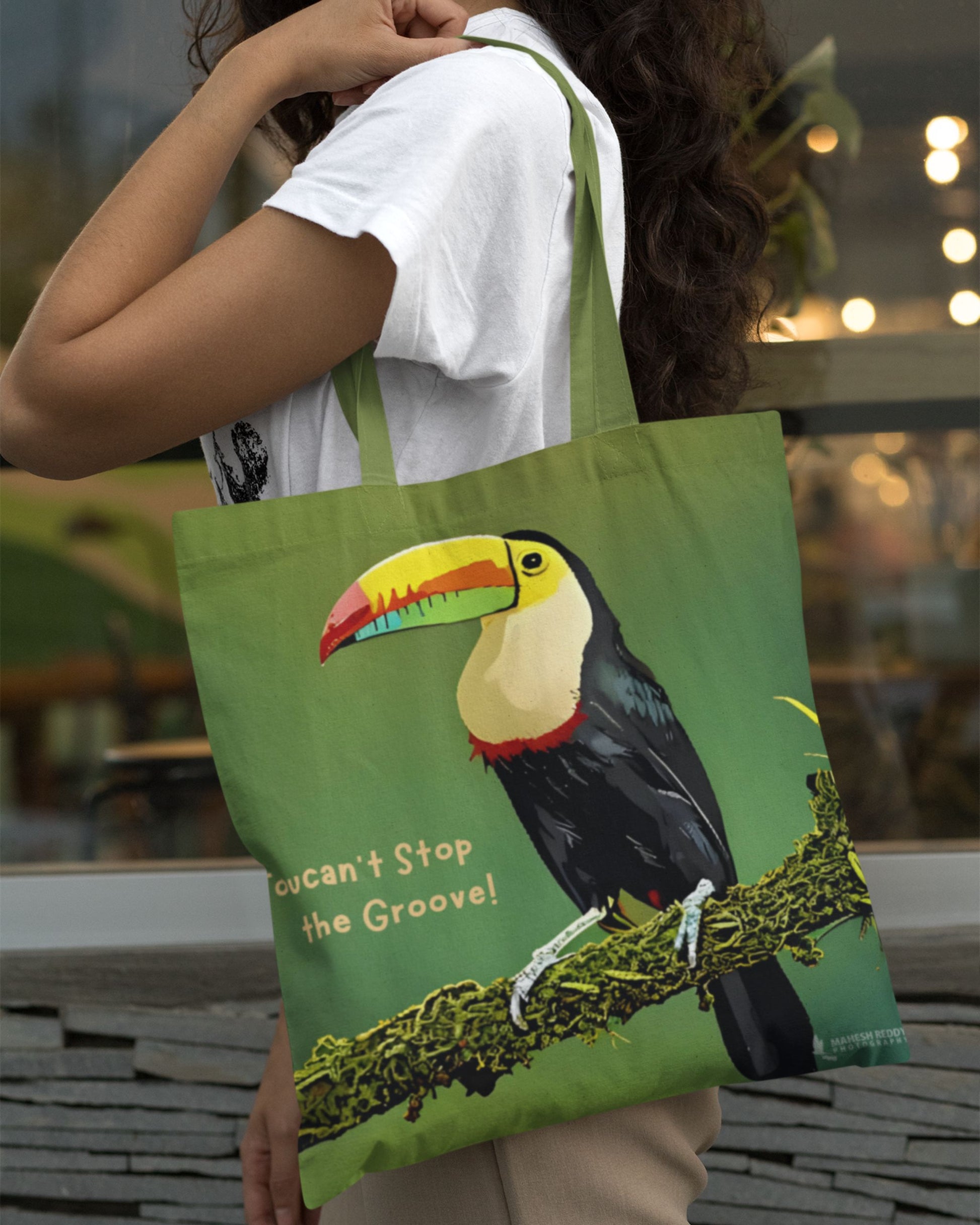 Person holding a green tucktribe tote bag with a toucan design and text.