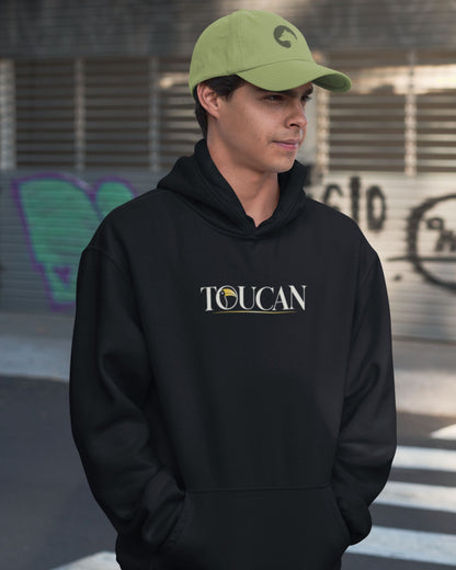 man wearing a green cap and a Black oversized unisex hoodie with colourful toucan and tropical rainforest wildlife graphic inspired by Mahesh Reddy photography