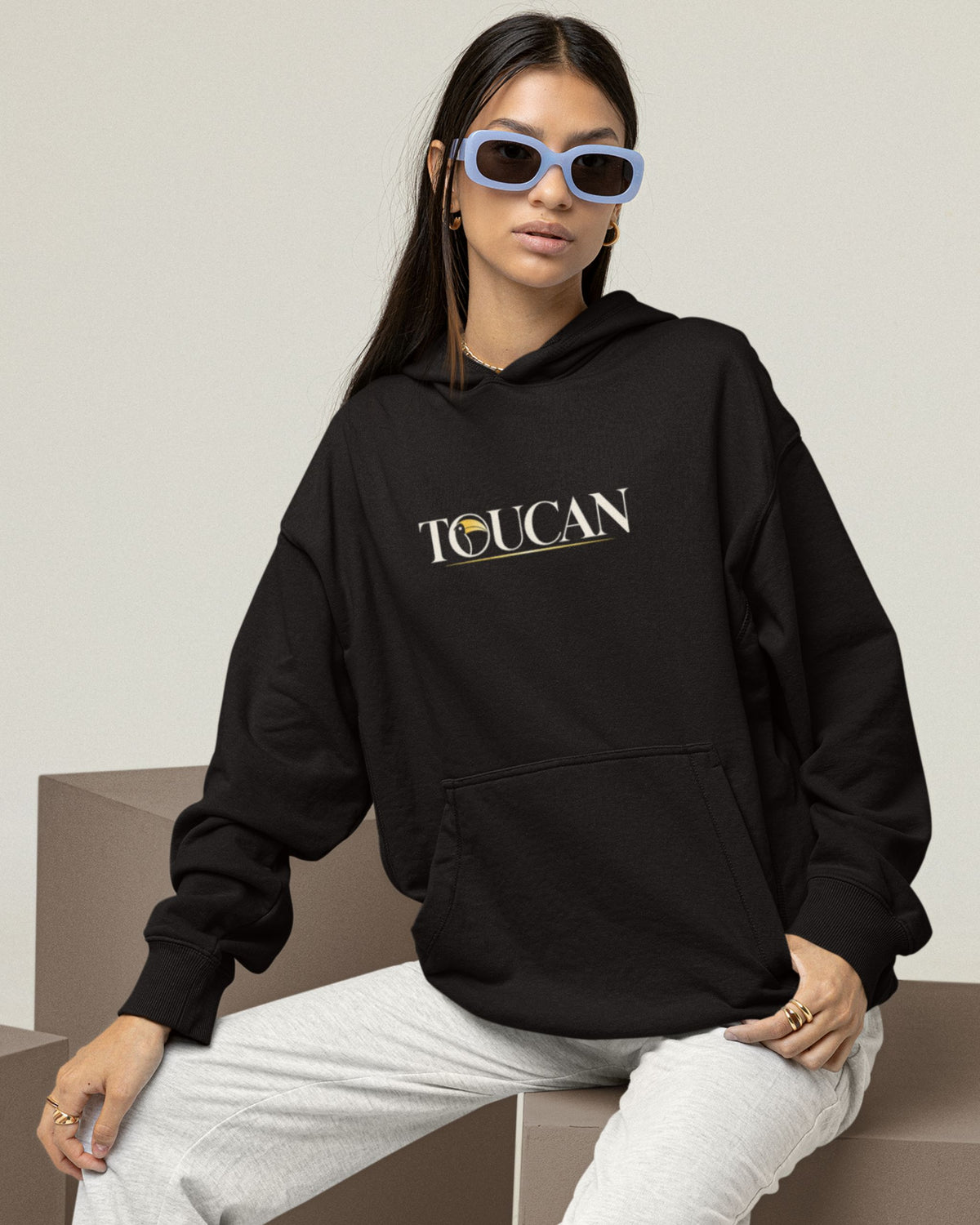 woman wearing a Black oversized unisex hoodie with colourful toucan and tropical rainforest wildlife graphic inspired by Mahesh Reddy photography