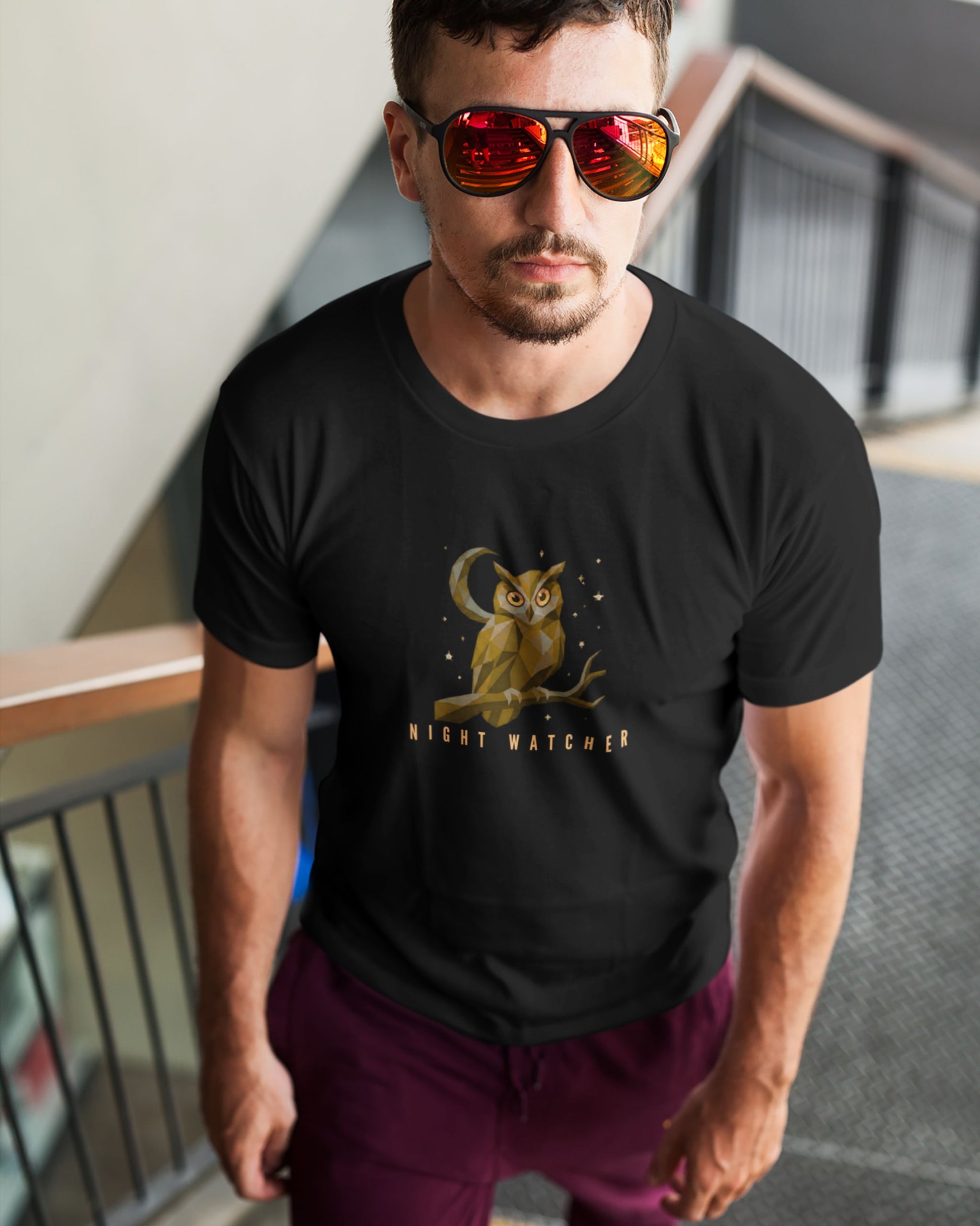 Man wearing a black tucktribe t-shirt with an owl graphic and 'Night Watcher' text, standing indoors.