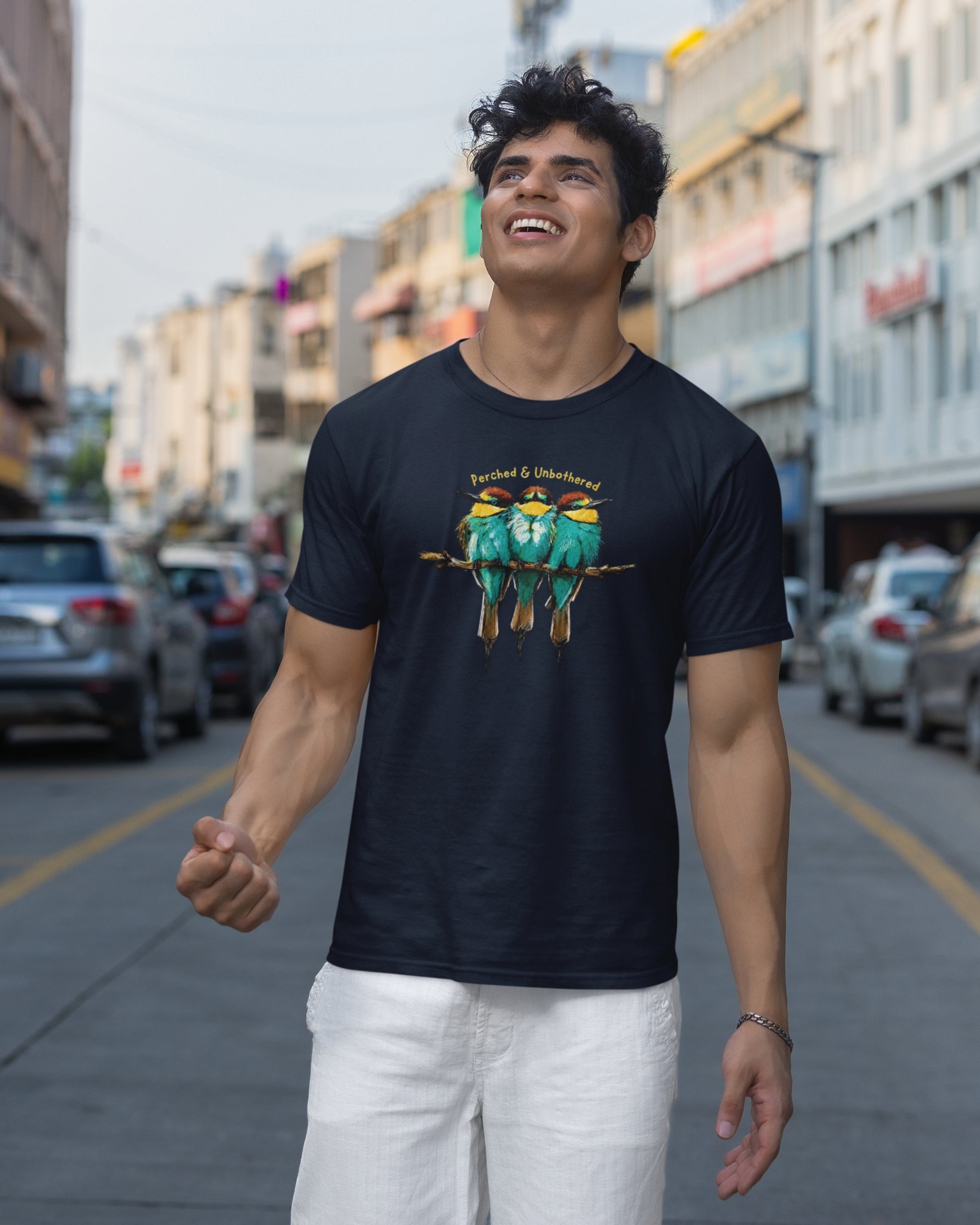 Man wearing a navyblue tucktribe Bee-Eater unisex T-shirt featuring colourful bird wildlife artwork inspired by Rashmi Dsouza