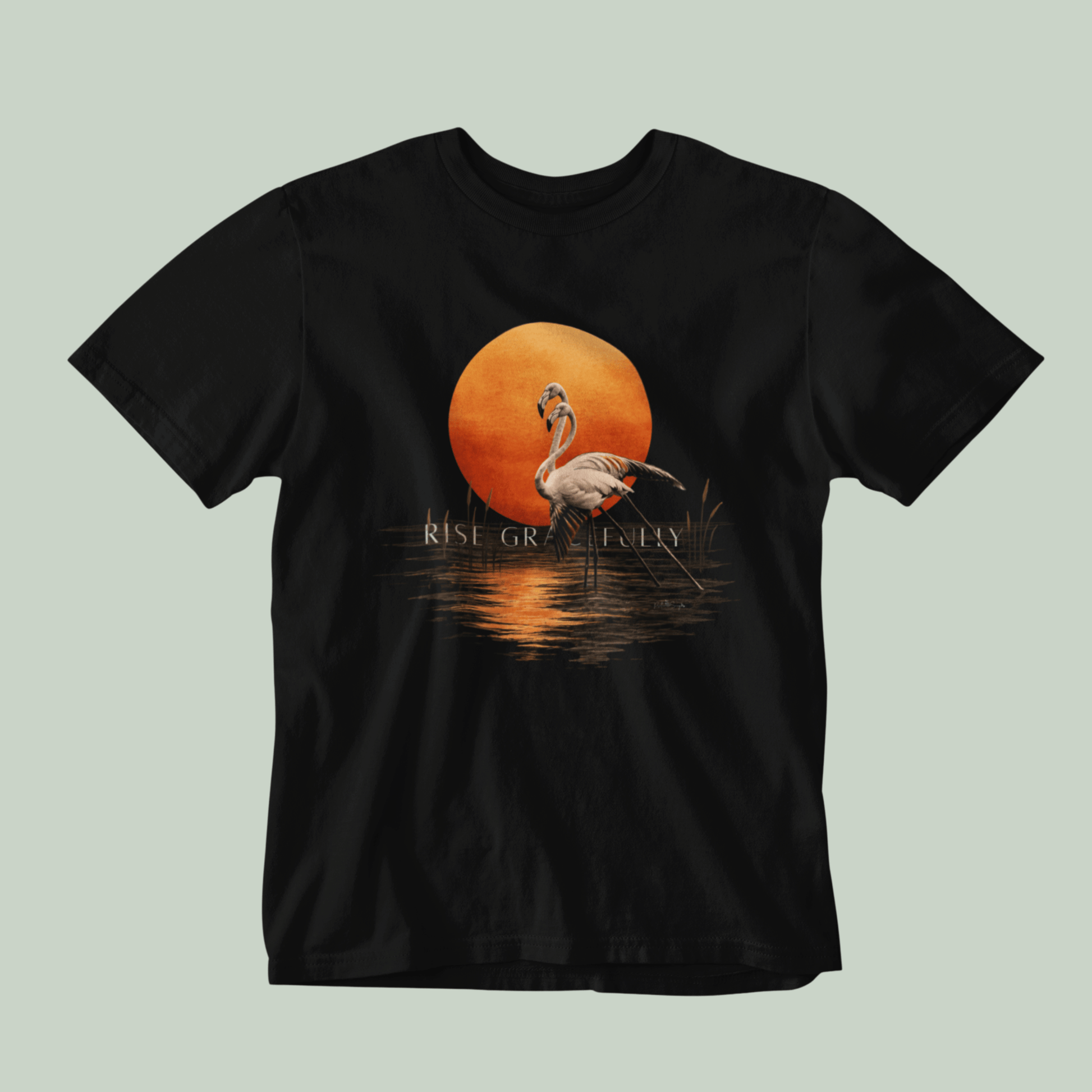 A black Tucktribe short-sleeve crewneck t-shirt featuring a graphic print of a pink flamingo standing in front of a large orange sun over water, with the text 'RISE GRACEFULLY' printed below the sun.