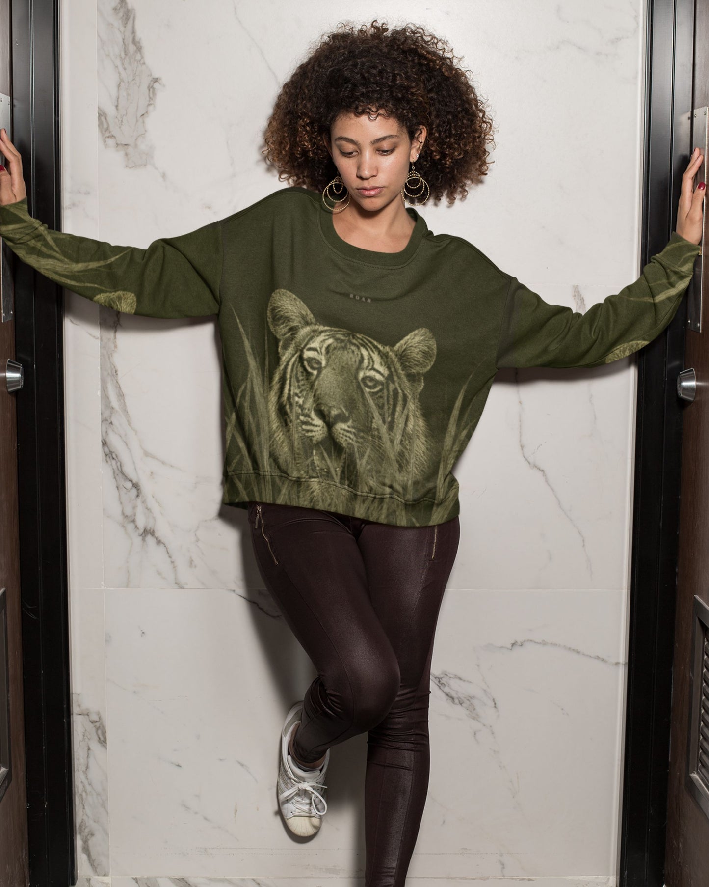 Woman wearing a Premium Bengal tiger emerging through tall grass on a wildlife-inspired unisex sweatshirt