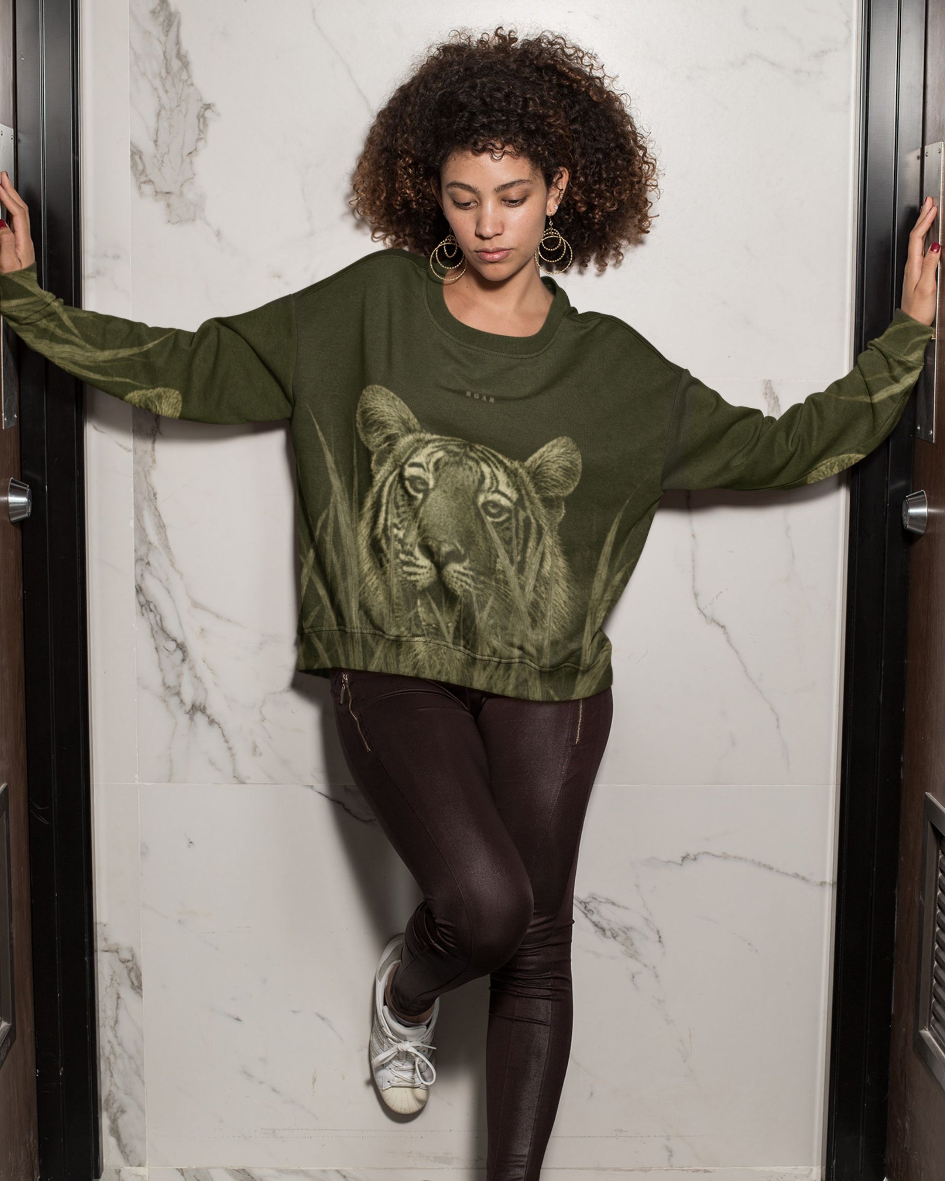 Woman wearing a Premium Bengal tiger emerging through tall grass on a wildlife-inspired unisex sweatshirt