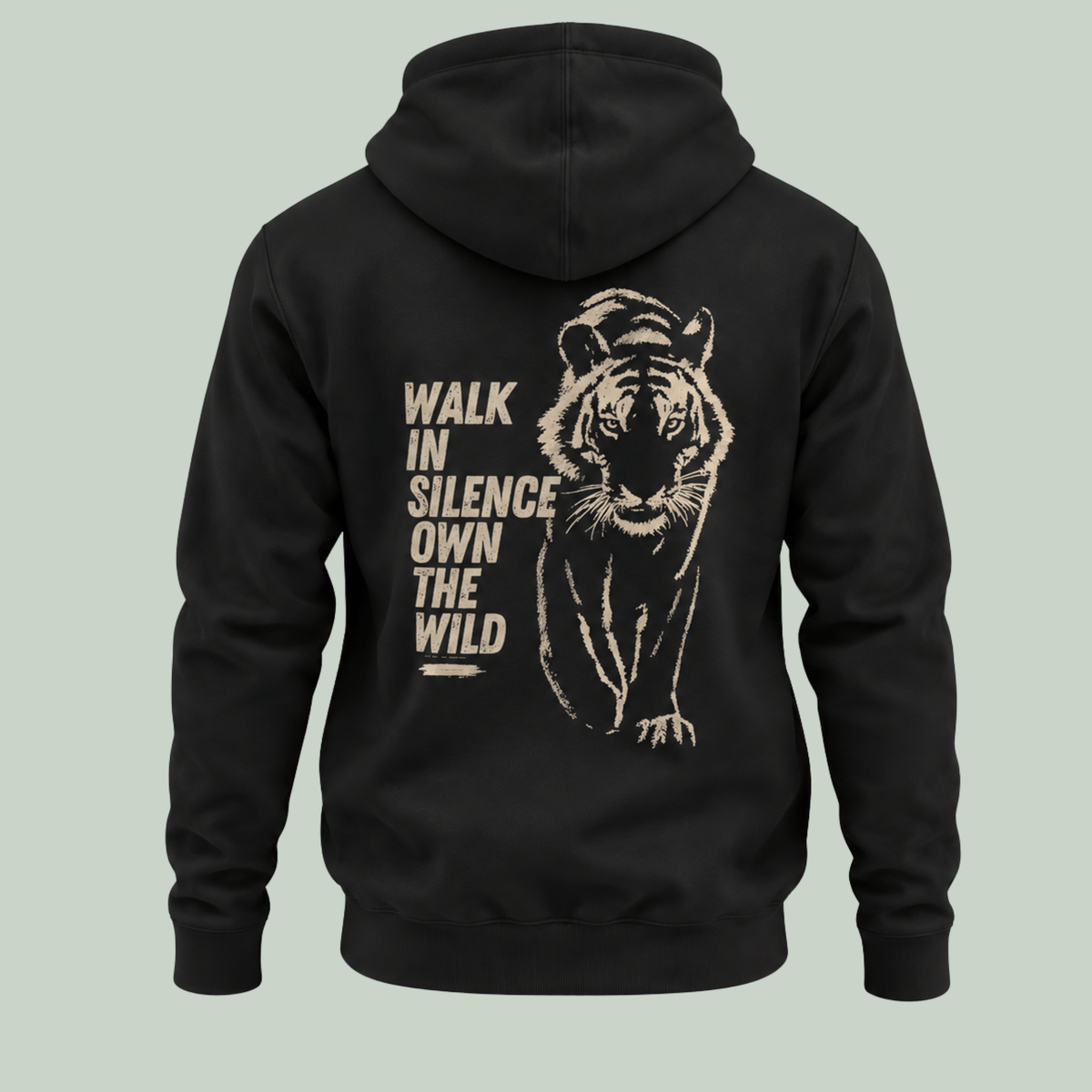 A black pullover hoodie shown from the back, featuring a large distressed beige graphic of a walking tiger and the text 'WALK IN SILENCE OWN THE WILD' on a light sage green background.