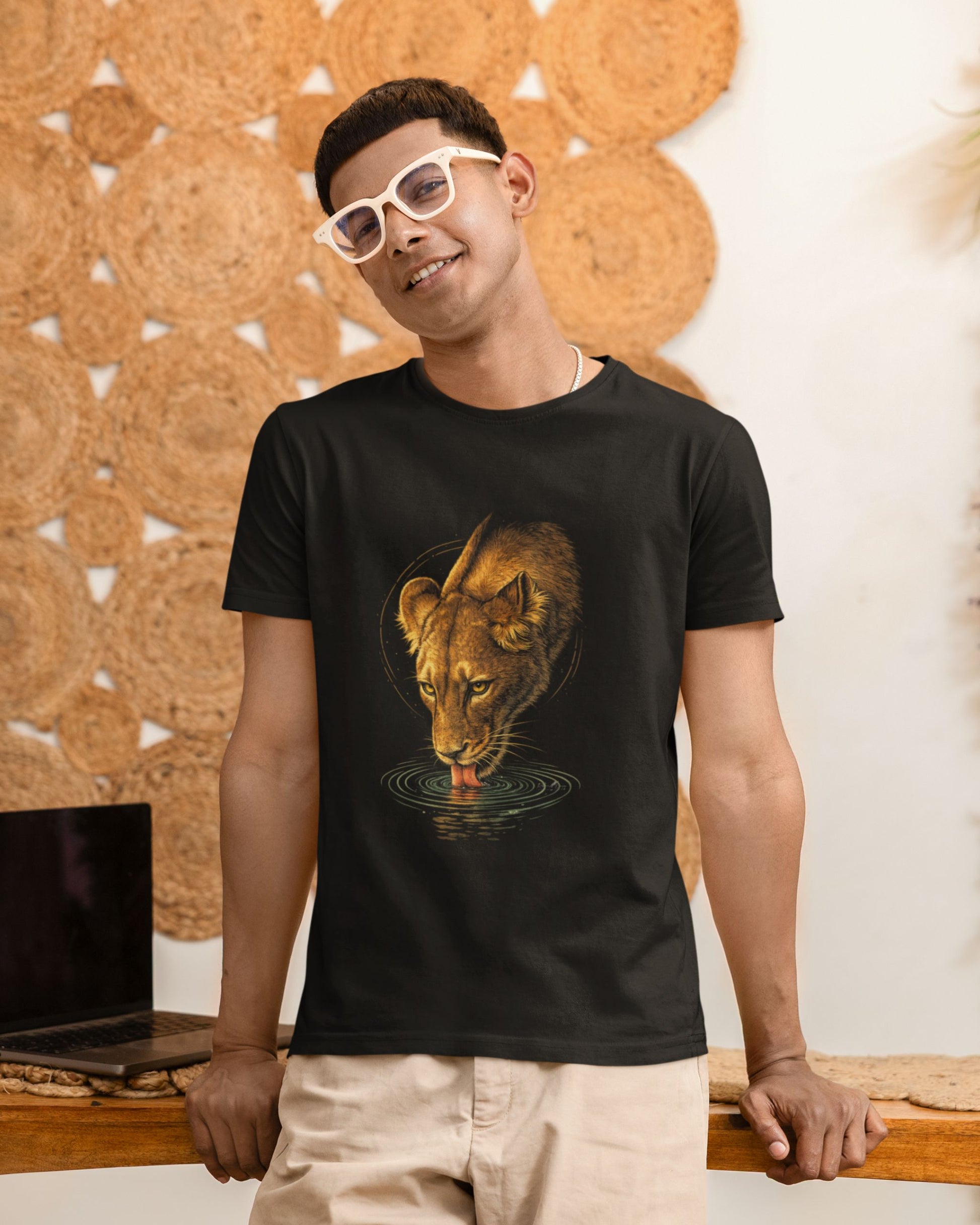 man wearing a black tucktribe t-shirt with a lioness graphic design, standing indoors.