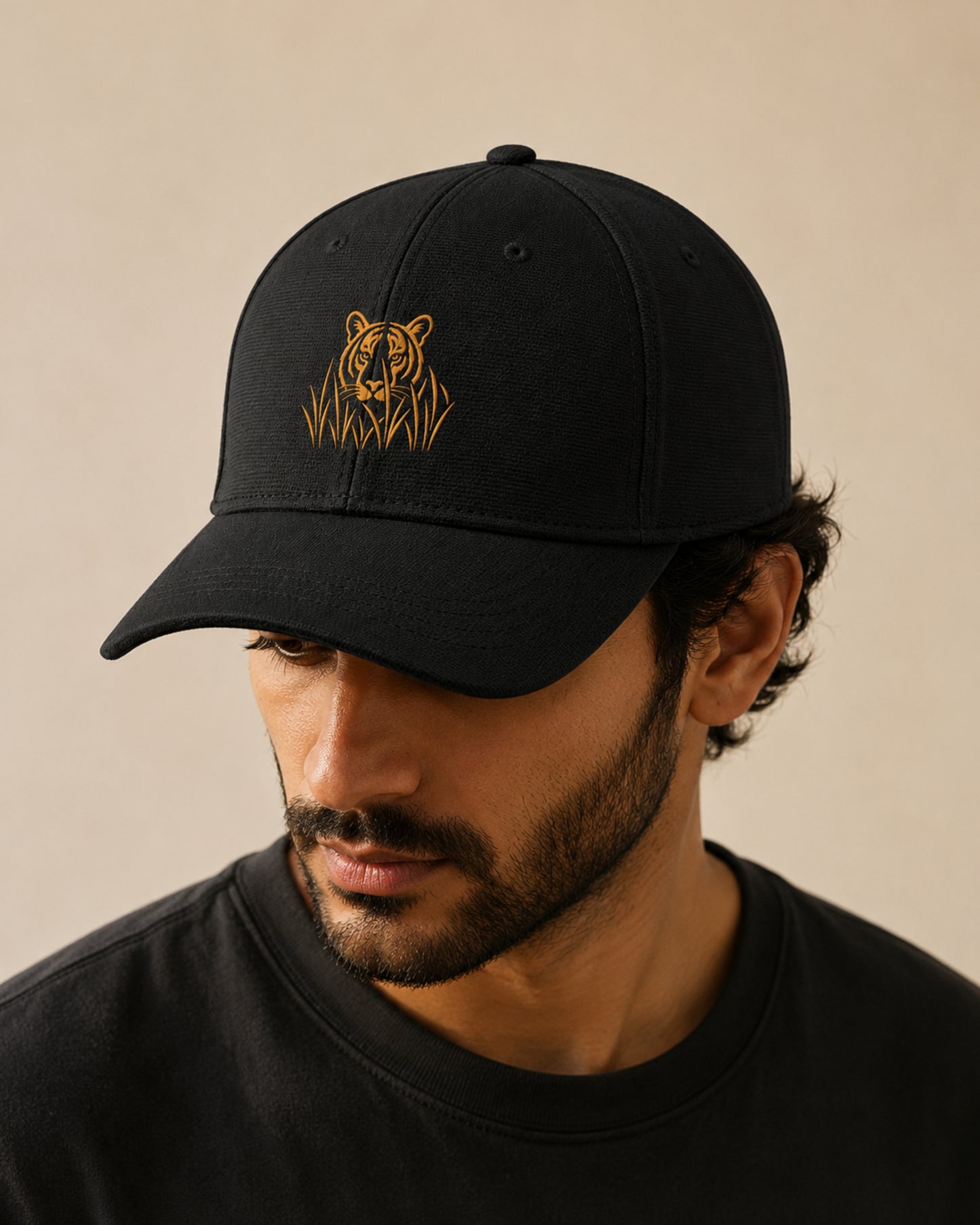 Model wearing a Black Ottoman cap with golden embroidered stalking tiger emerging through grass