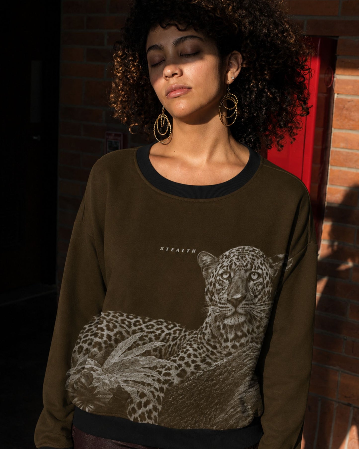 Woman wearing a detailed leopard resting on a tree wildlife artwork featured on a premium unisex sweatshirt by Tucktribe.