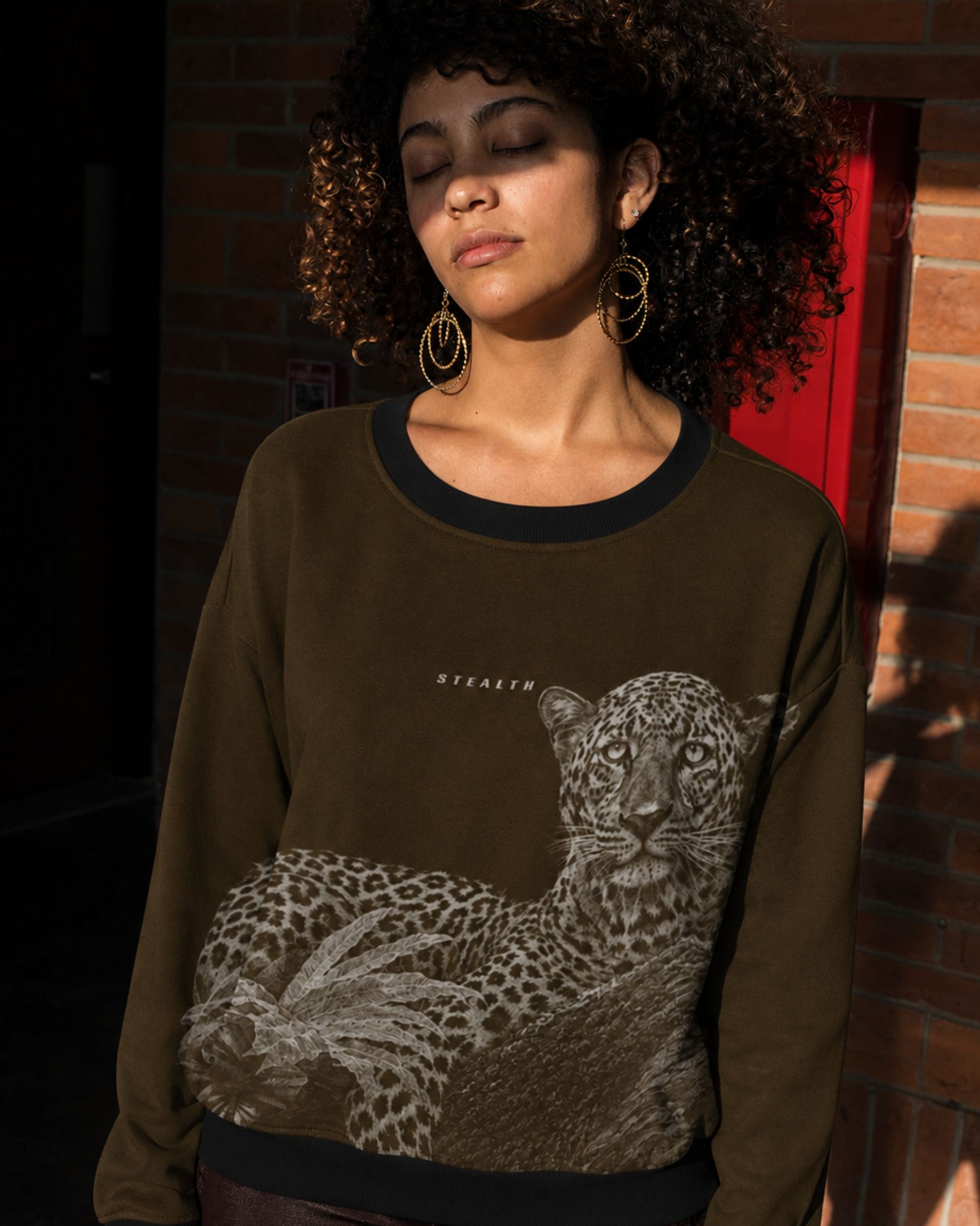 Woman wearing a detailed leopard resting on a tree wildlife artwork featured on a premium unisex sweatshirt by Tucktribe.