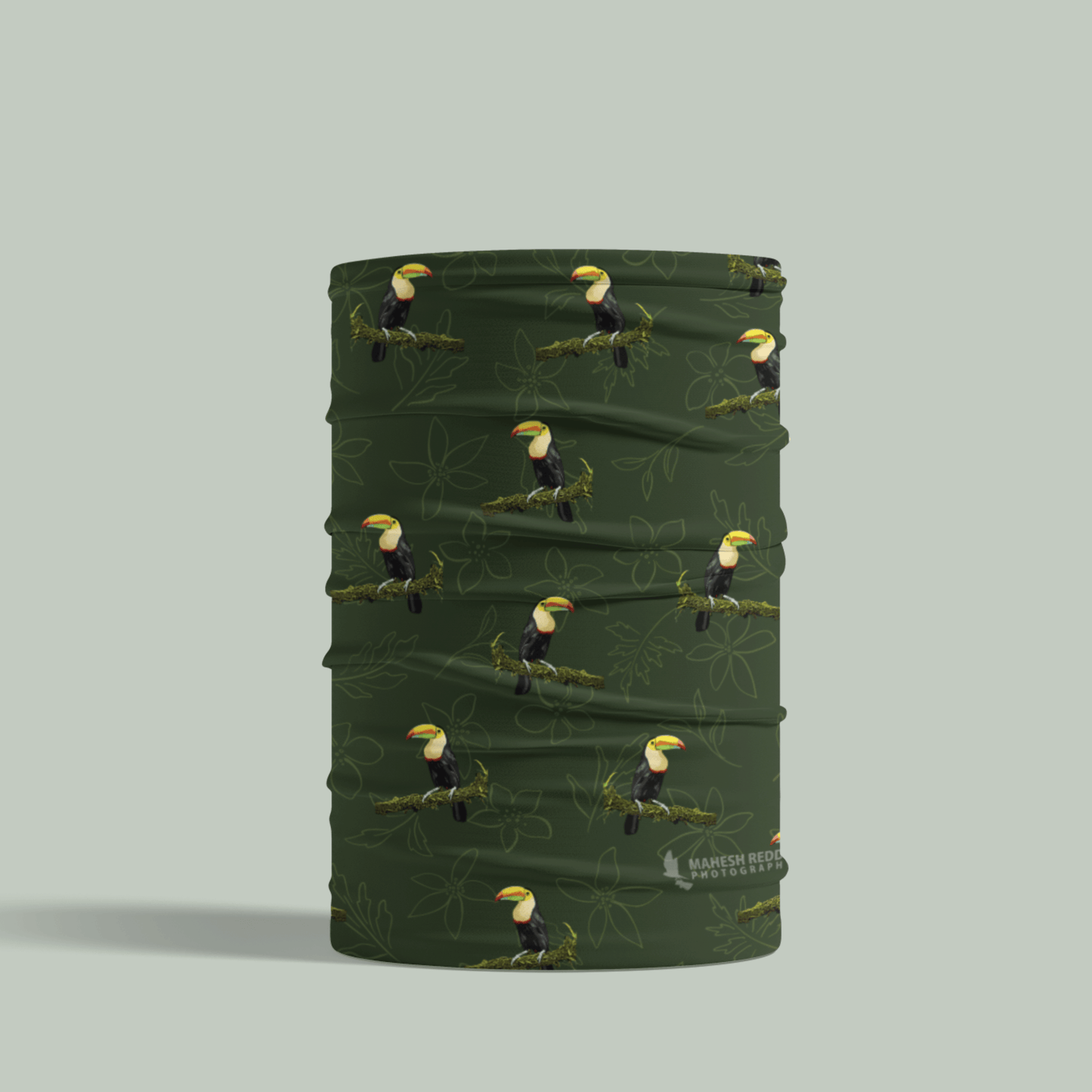 Green Tucktribe neck gaiter with toucan pattern on a light gray background