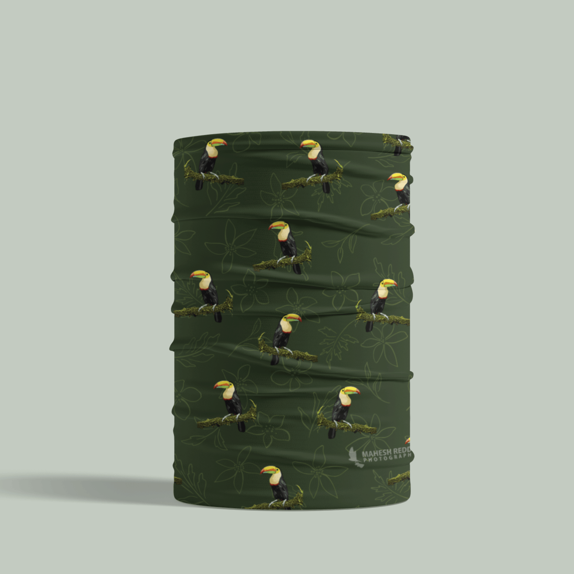 Green Tucktribe neck gaiter with toucan pattern on a light gray background