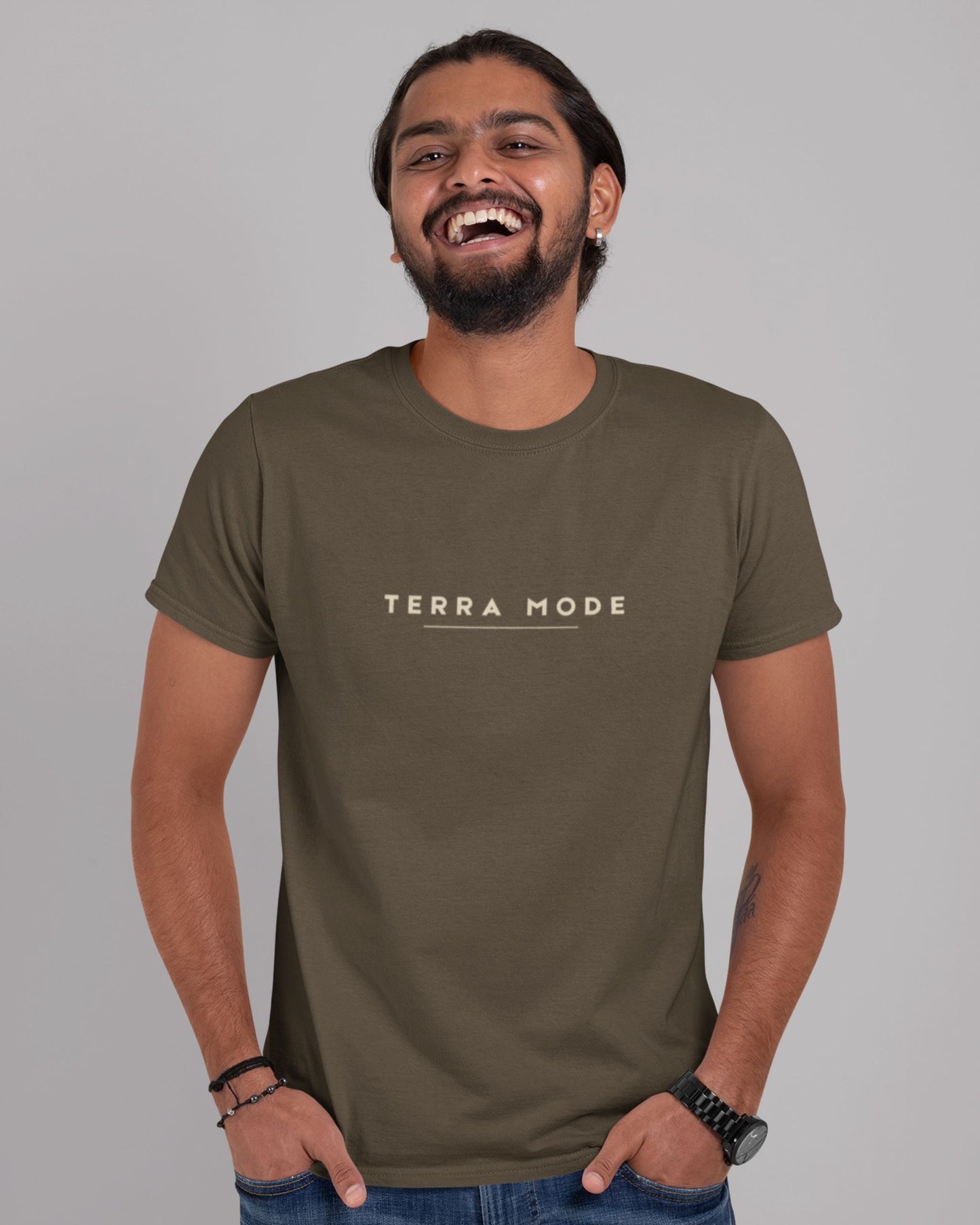 Person wearing a tucktribe olive green 'Terra Mode' t-shirt against a gray background