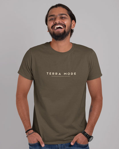 Person wearing a tucktribe olive green 'Terra Mode' t-shirt against a gray background