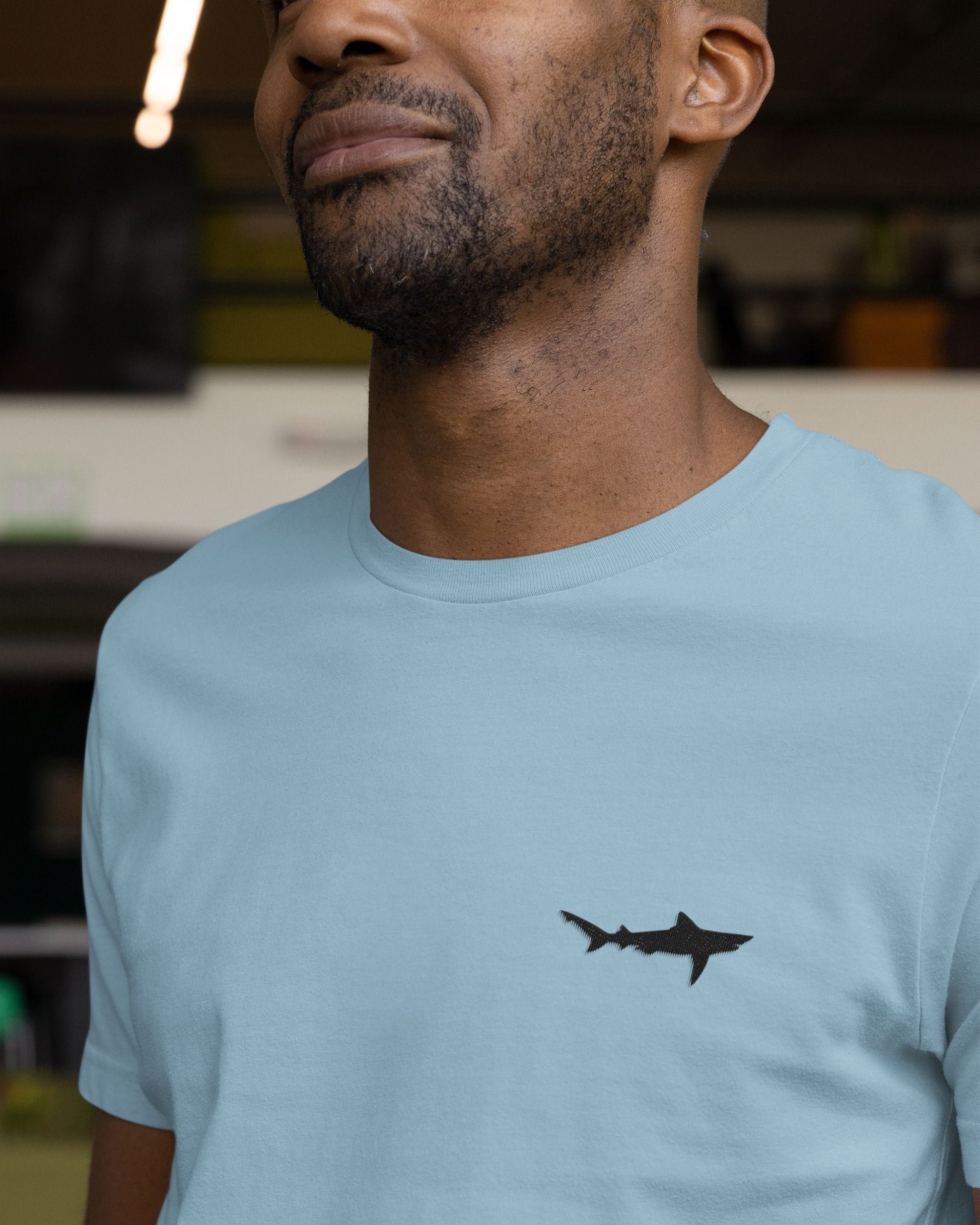 man wearing baby blue cotton stretch t-shirt with embroidered Ganges Shark wildlife design by Tucktribe