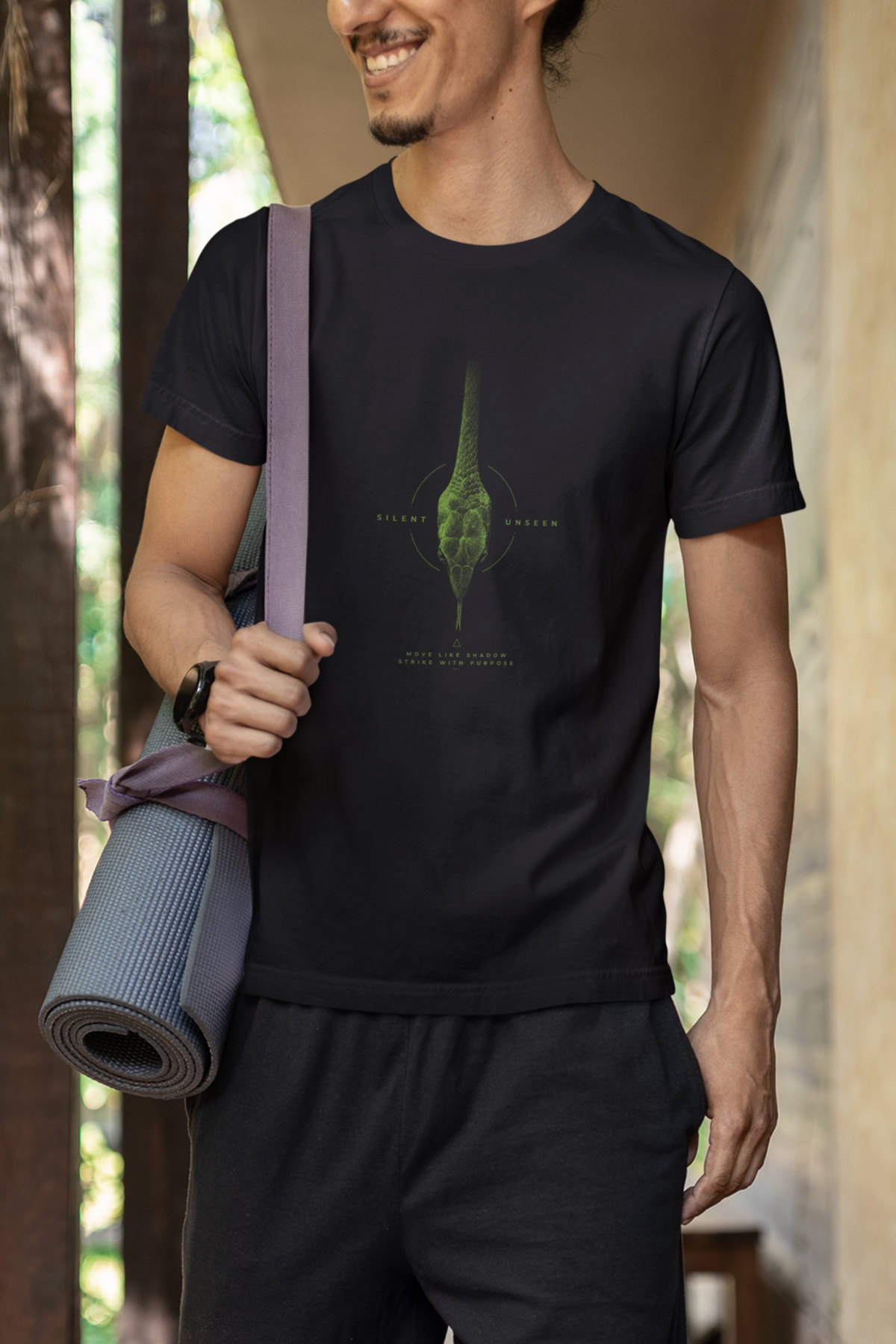 Man wearing a Black graphic T-shirt featuring detailed green vine snake artwork with Silent Unseen typography
