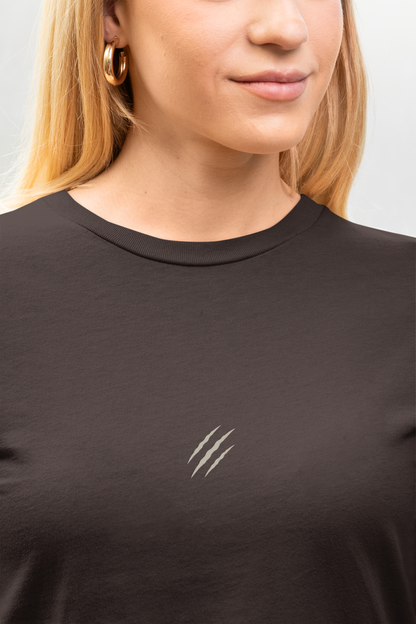 Person wearing a tucktribe brown t-shirt with a small white claw embroidery on a plain background