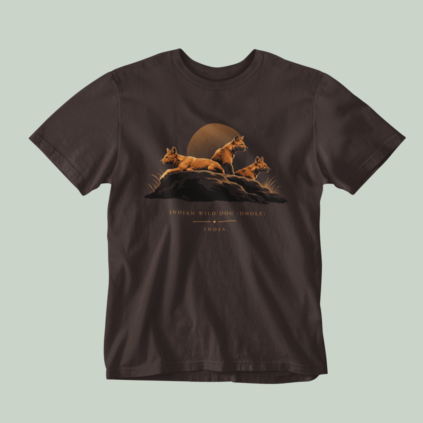 Dhole wildlife Brown T-shirt featuring three Indian wild dogs on a rocky landscape with sunset-inspired artwork