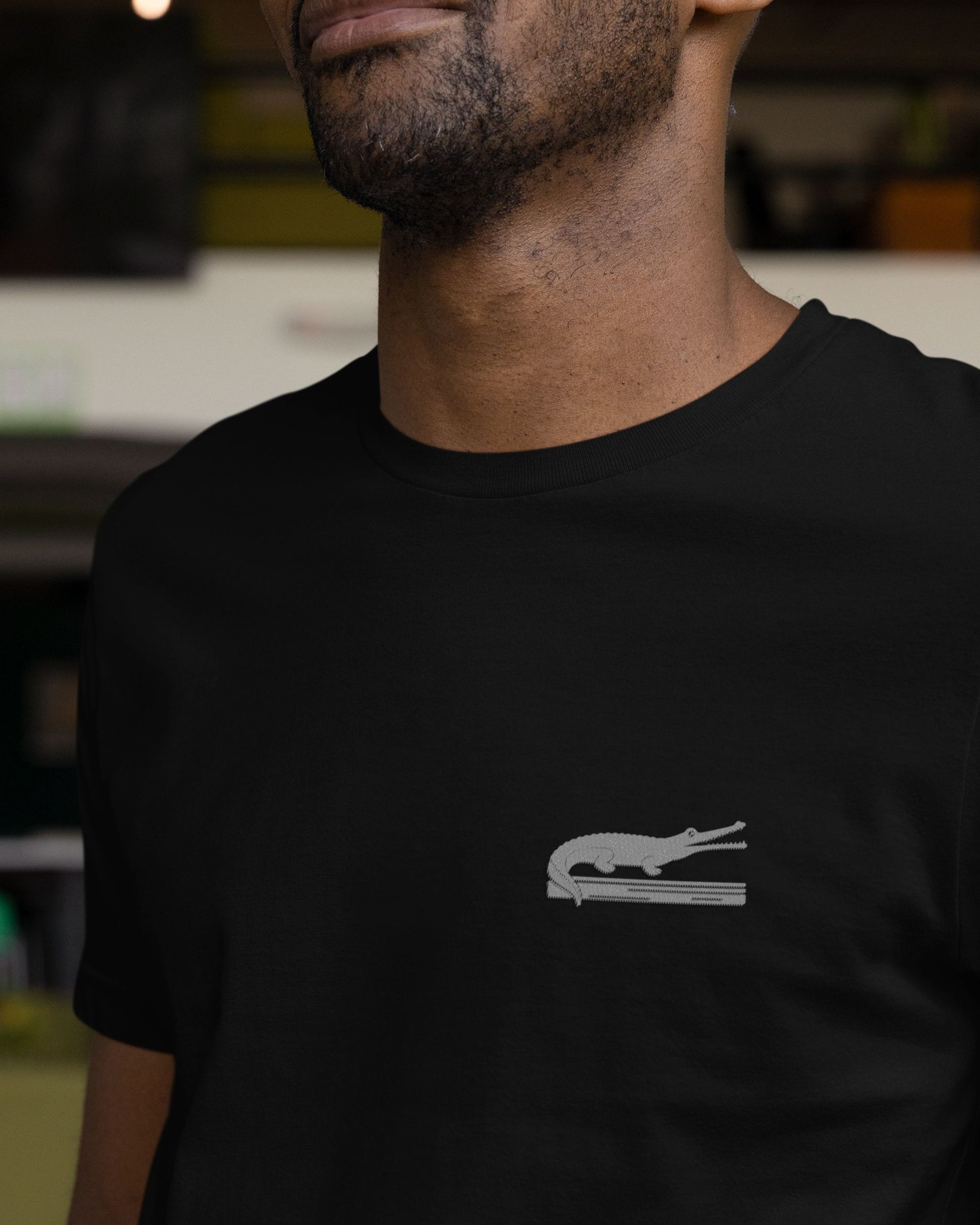 person wearing black cotton stretch t-shirt with embroidered Indian Gharial wildlife design by Tucktribe