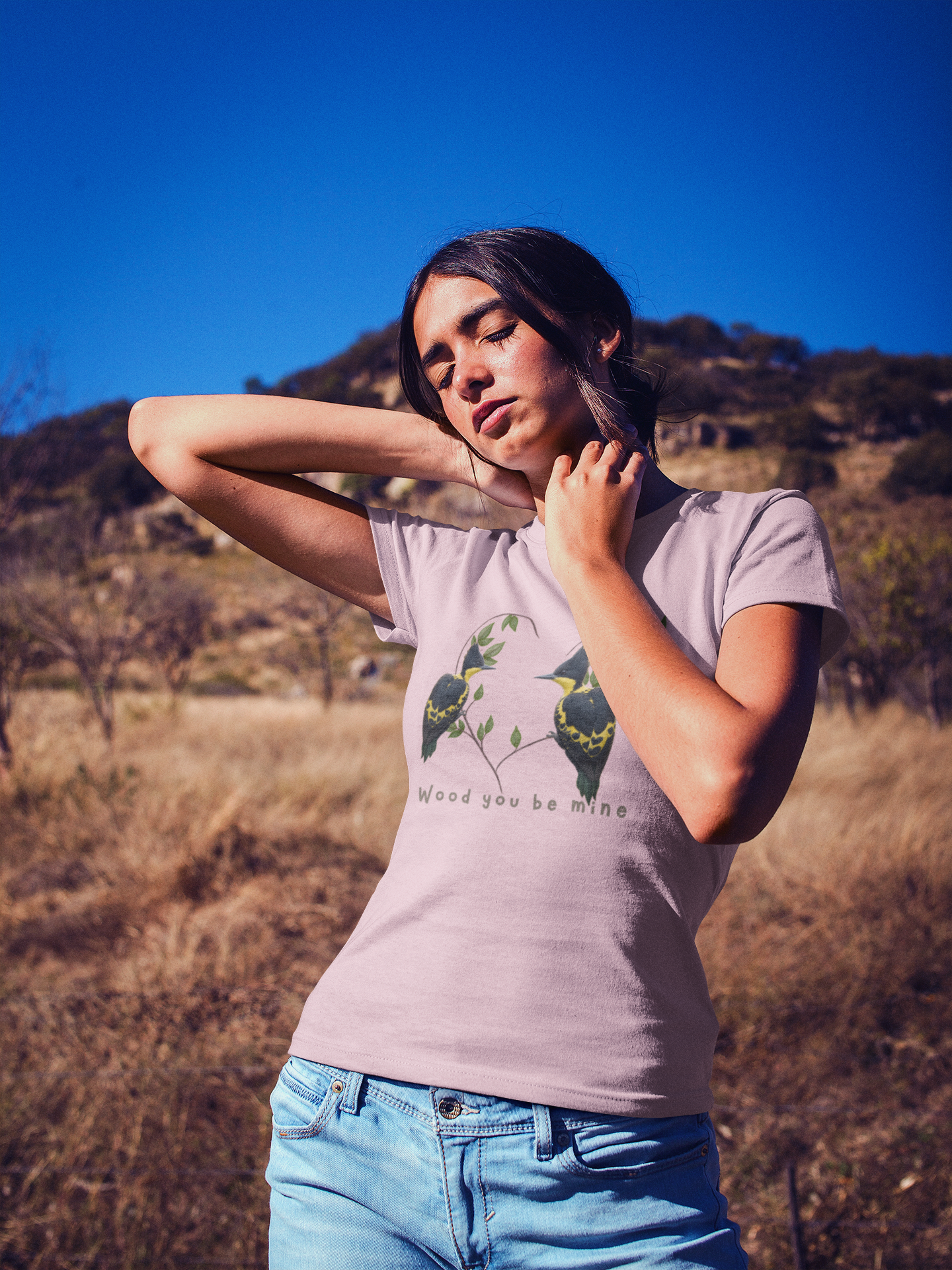 Woman wearing a pink t-shirt with a graphic design of birds outdoors