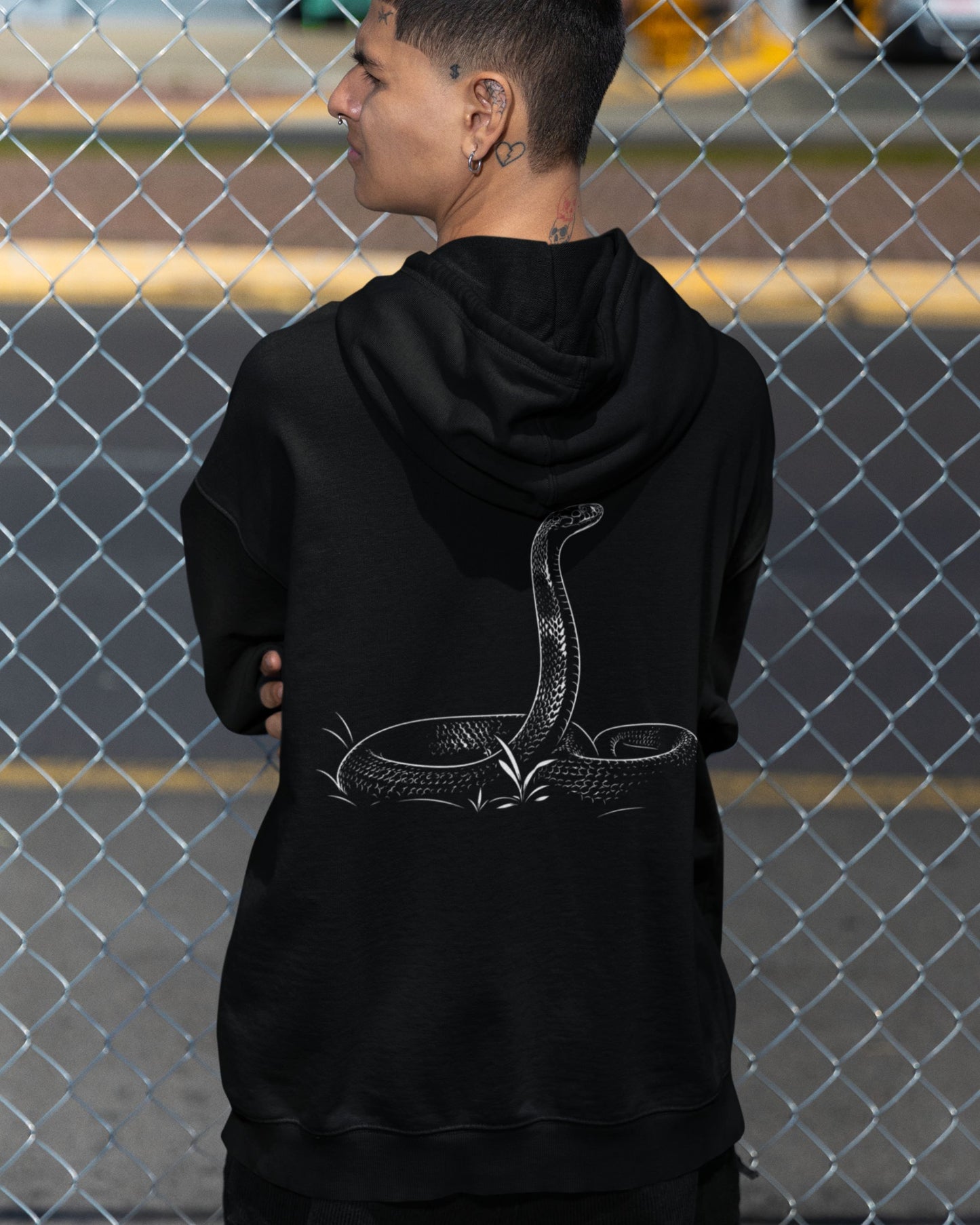 man wearing a Black tucktribe unisex hoodie featuring detailed cobra snake artwork on the back for wildlife lovers.
