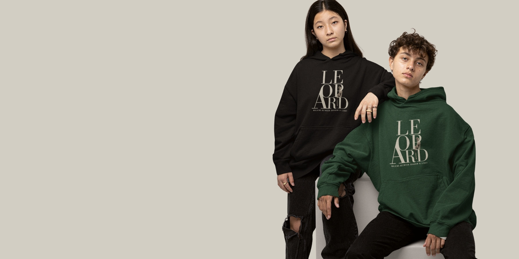 Banner image of Two models posing in oversized hoodies with 'LEOPARD' text. The model on the left wears a black hoodie, and the model on the right wears a forest green hoodie, both set against a solid light gray background.
