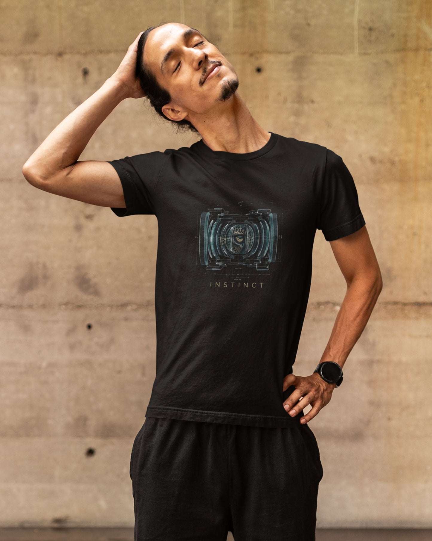 Man wearing a black tucktribe t-shirt with a graphic design against a concrete wall.