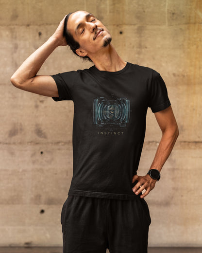 Man wearing a black tucktribe t-shirt with a graphic design against a concrete wall.