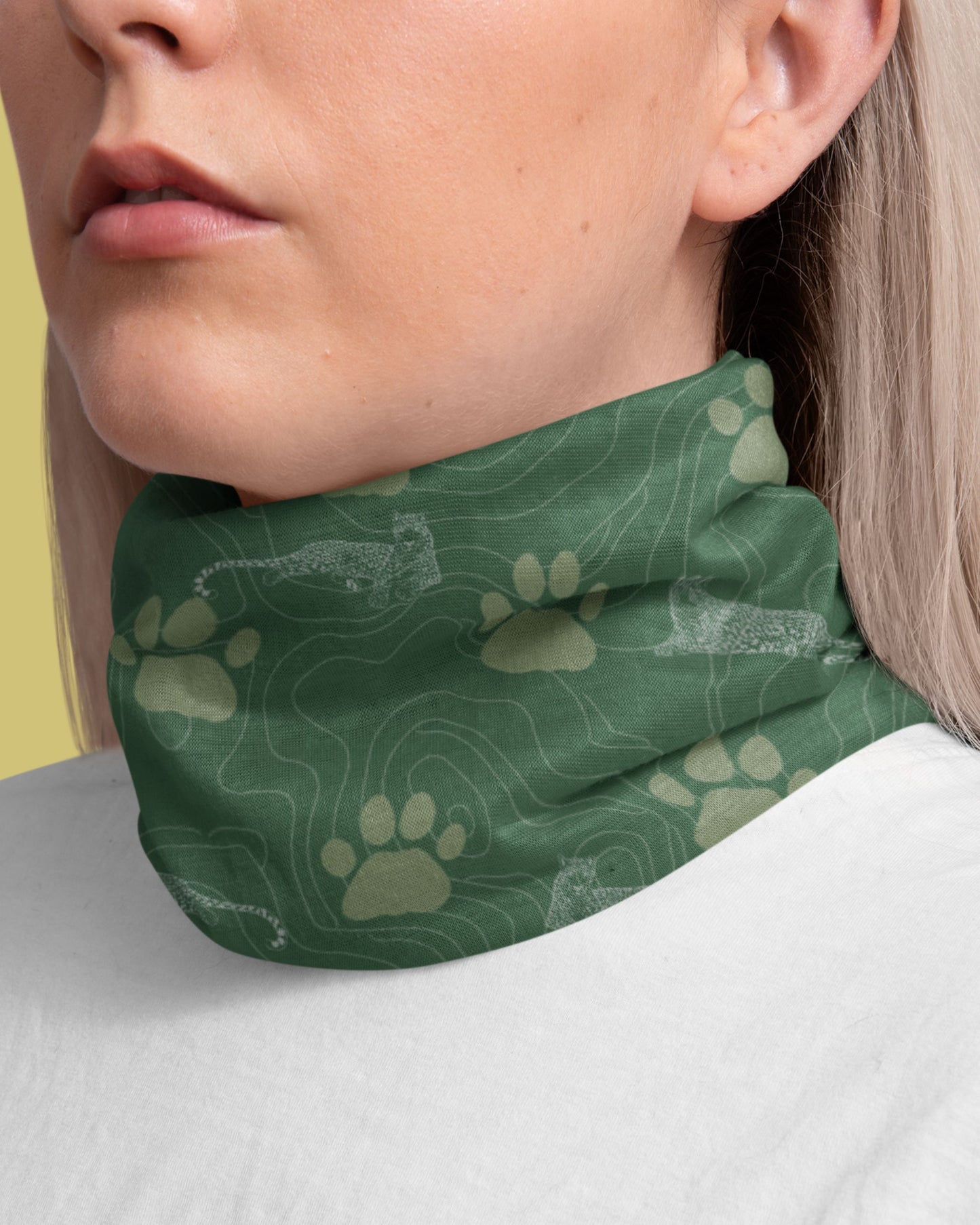 Person wearing a Green Tucktribe neck gaiter with leopard paw print pattern  around her neck.