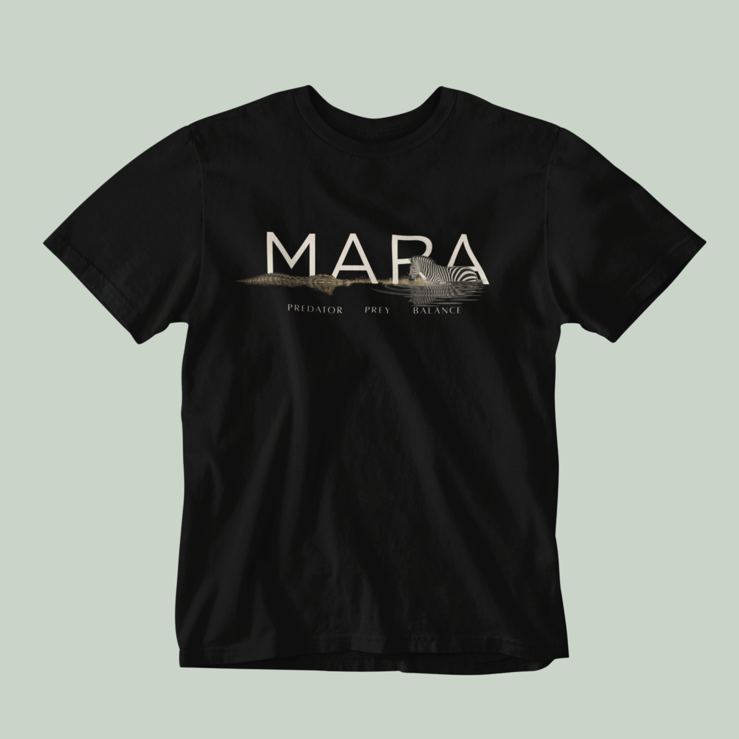 A black Tucktribe short-sleeve crewneck t-shirt with a beige graphic print on the chest featuring the word 'MARA' and smaller text 'PREDATOR - PREY- BALANCE' with a Zebra and crocodile illustration, displayed against a solid light sage green background.