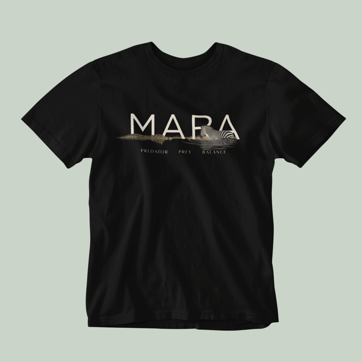 A black Tucktribe short-sleeve crewneck t-shirt with a beige graphic print on the chest featuring the word 'MARA' and smaller text 'PREDATOR - PREY- BALANCE' with a Zebra and crocodile illustration, displayed against a solid light sage green background.